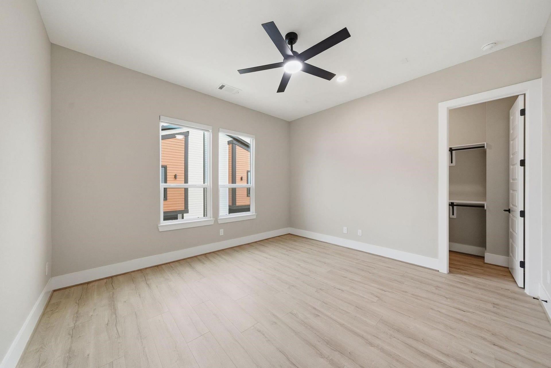 4013 Griggs Road, #F, Houston, TX 77021 Spacious bedroom with elegant hardwood flooring, modern ceiling fan, and ample natural light from large windows, featuring a walk-in closet for added convenience.