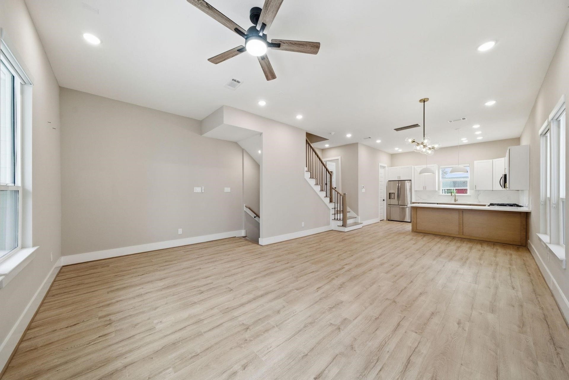 4013 Griggs Road, #F, Houston, TX 77021 Spacious open-concept living area with modern kitchen, featuring sleek cabinetry, stainless steel appliances, and elegant lighting, complemented by warm wood flooring and abundant natural light.