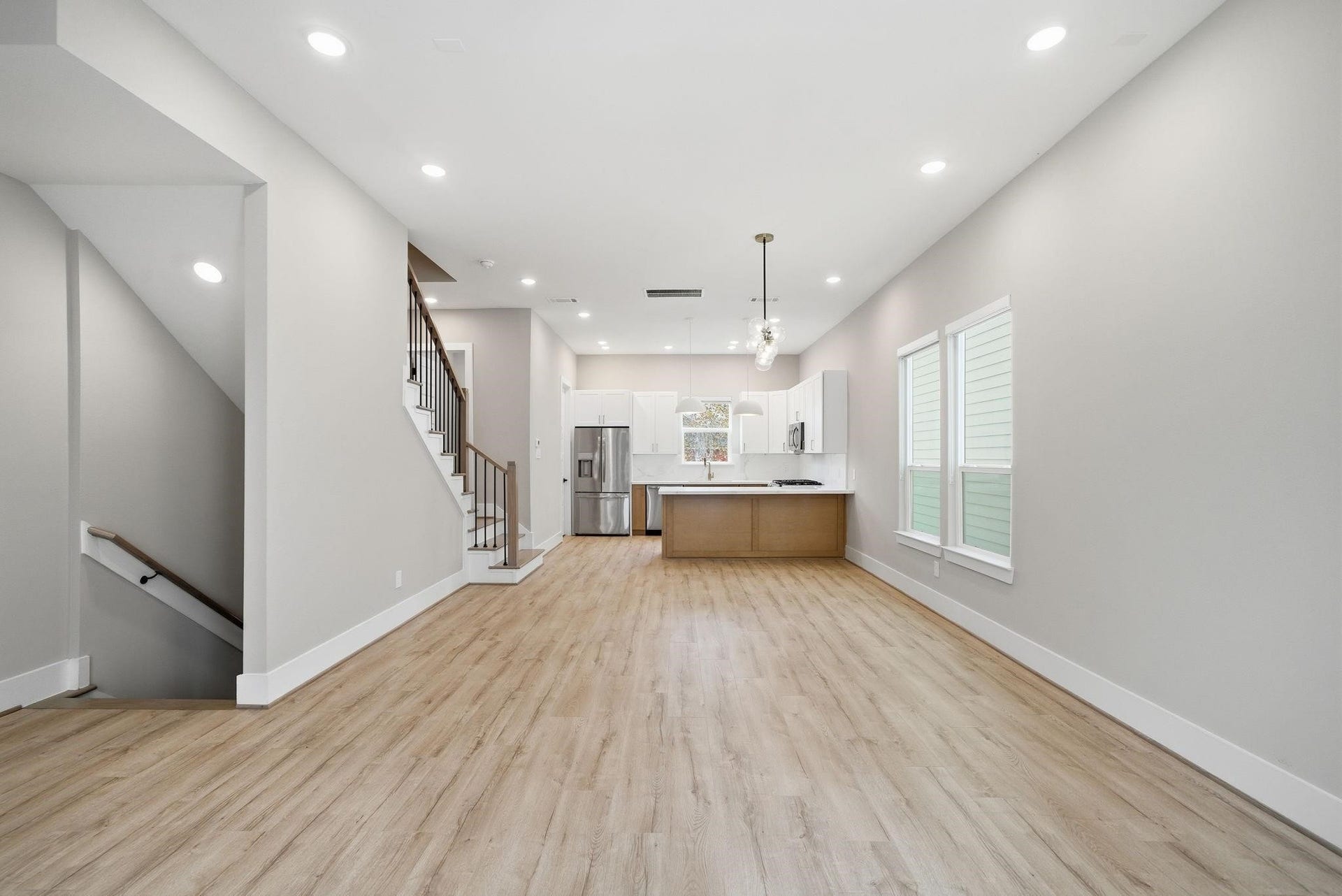 4013 Griggs Road, #F, Houston, TX 77021 Bright and airy open-concept living area with sleek wood flooring, modern recessed lighting, and a stylish kitchen featuring stainless steel appliances and a central island, perfect for entertaining.