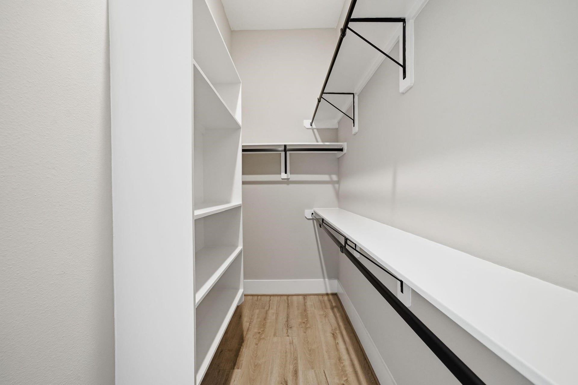 4013 Griggs Road, #F, Houston, TX 77021 Spacious walk-in closet with ample shelving and hanging space, featuring sleek white finishes and a light wood floor.