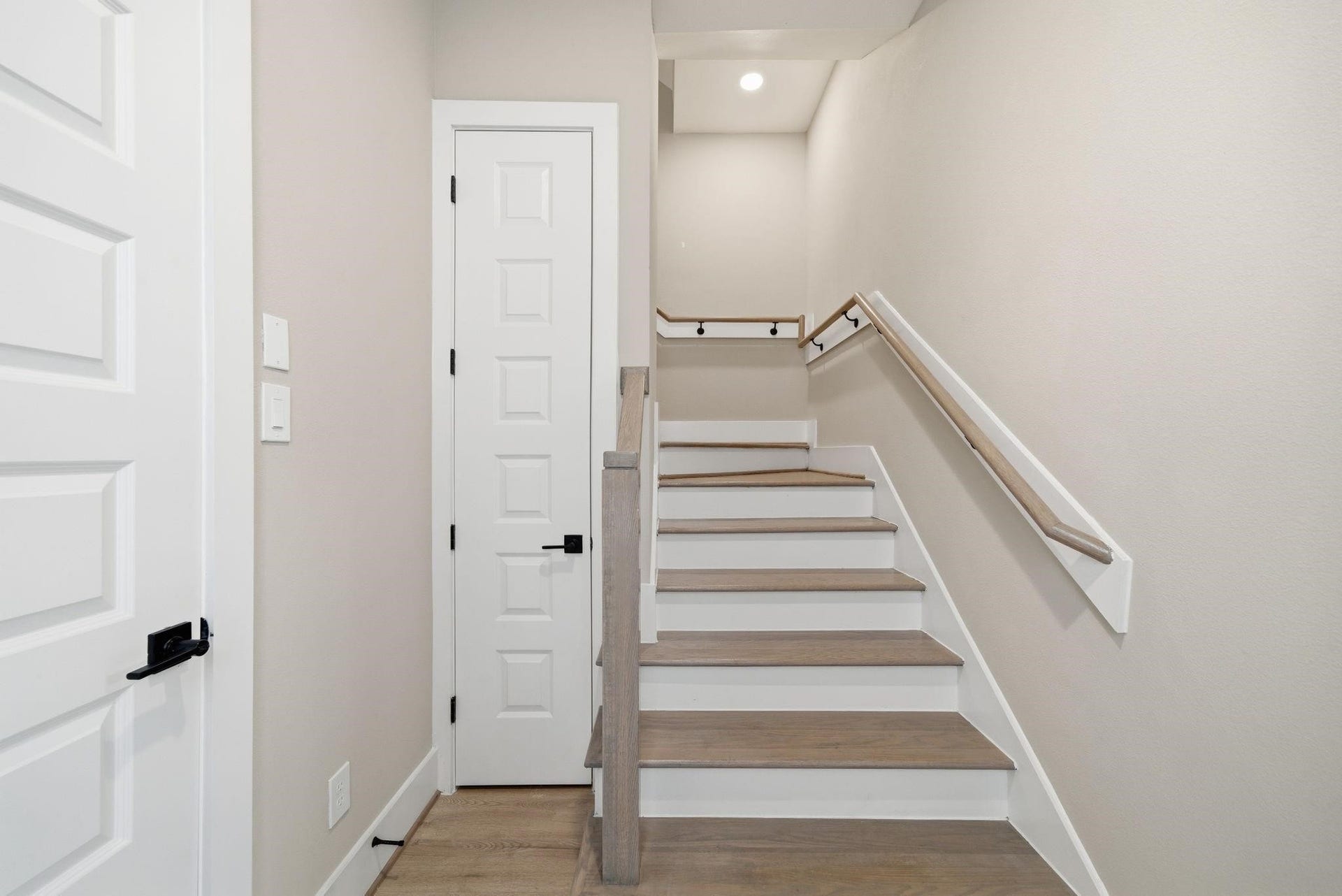 4013 Griggs Road, #F, Houston, TX 77021 Modern staircase with sleek wood steps and matching handrails, complemented by crisp white accents and soft neutral walls.
