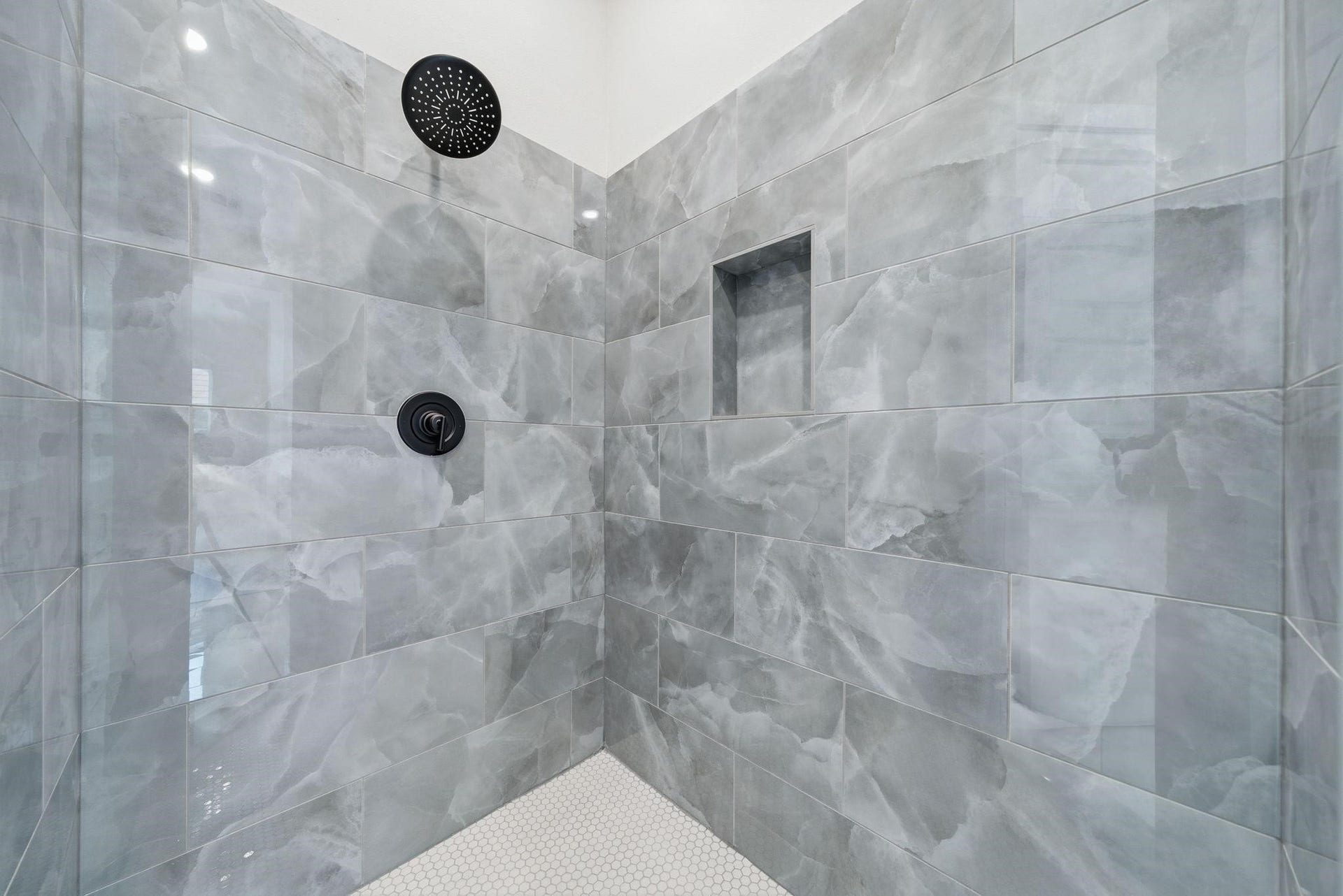 4013 Griggs Road, #F, Houston, TX 77021 Luxurious shower featuring elegant gray marble tiles, a sleek rain shower head, and a convenient recessed shelf for toiletries.