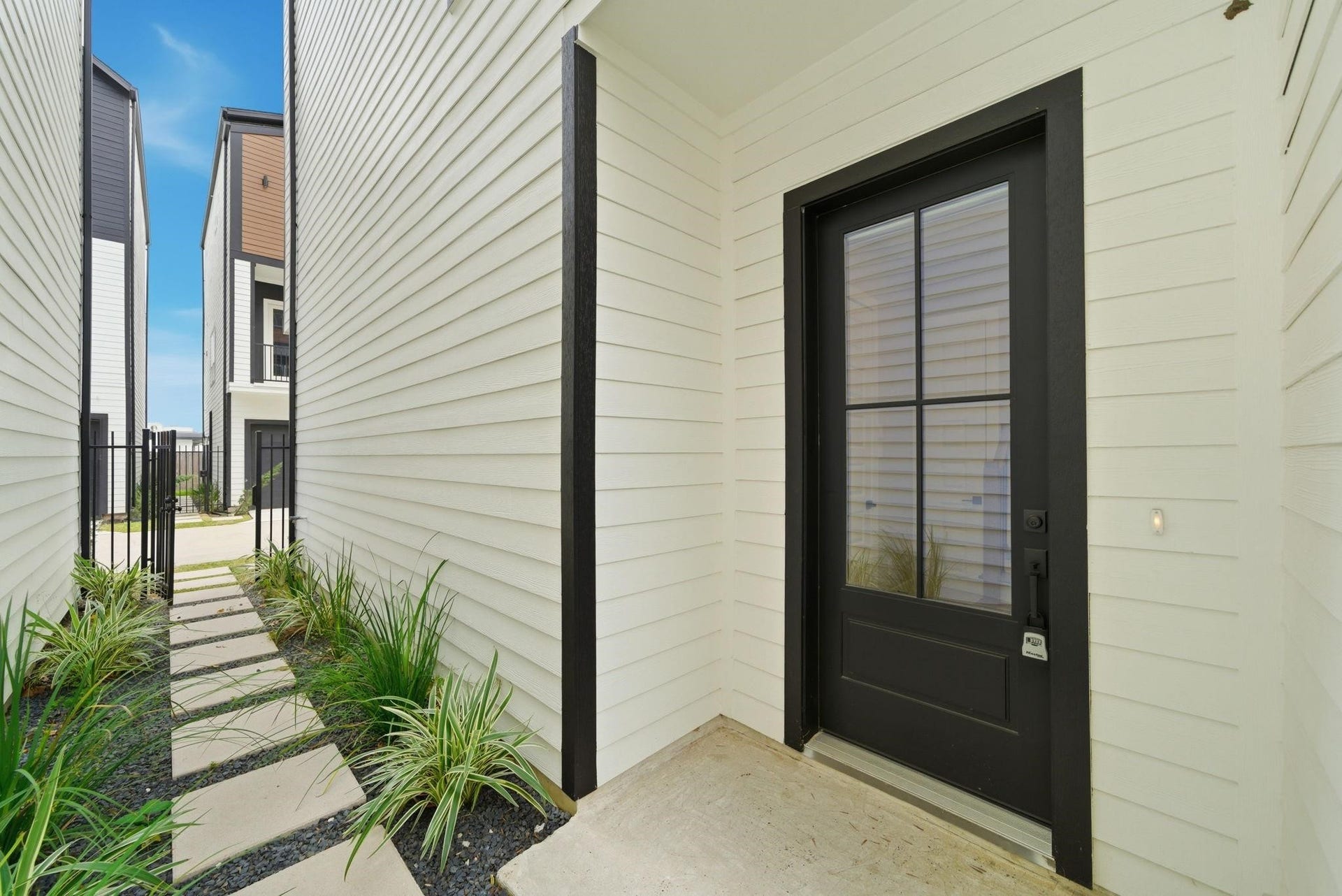 4013 Griggs Road, #F, Houston, TX 77021 Charming entrance with a sleek black door and modern glass panels, lined with contemporary siding and a neat paved pathway.