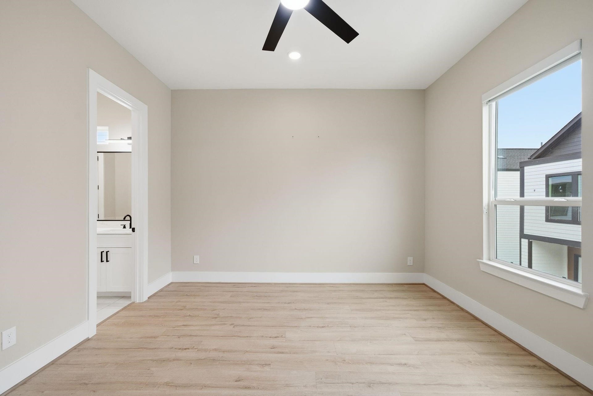 4013 Griggs Road, #F, Houston, TX 77021 Bright and spacious bedroom featuring sleek hardwood floors, a modern ceiling fan, and an en-suite bathroom for added convenience.