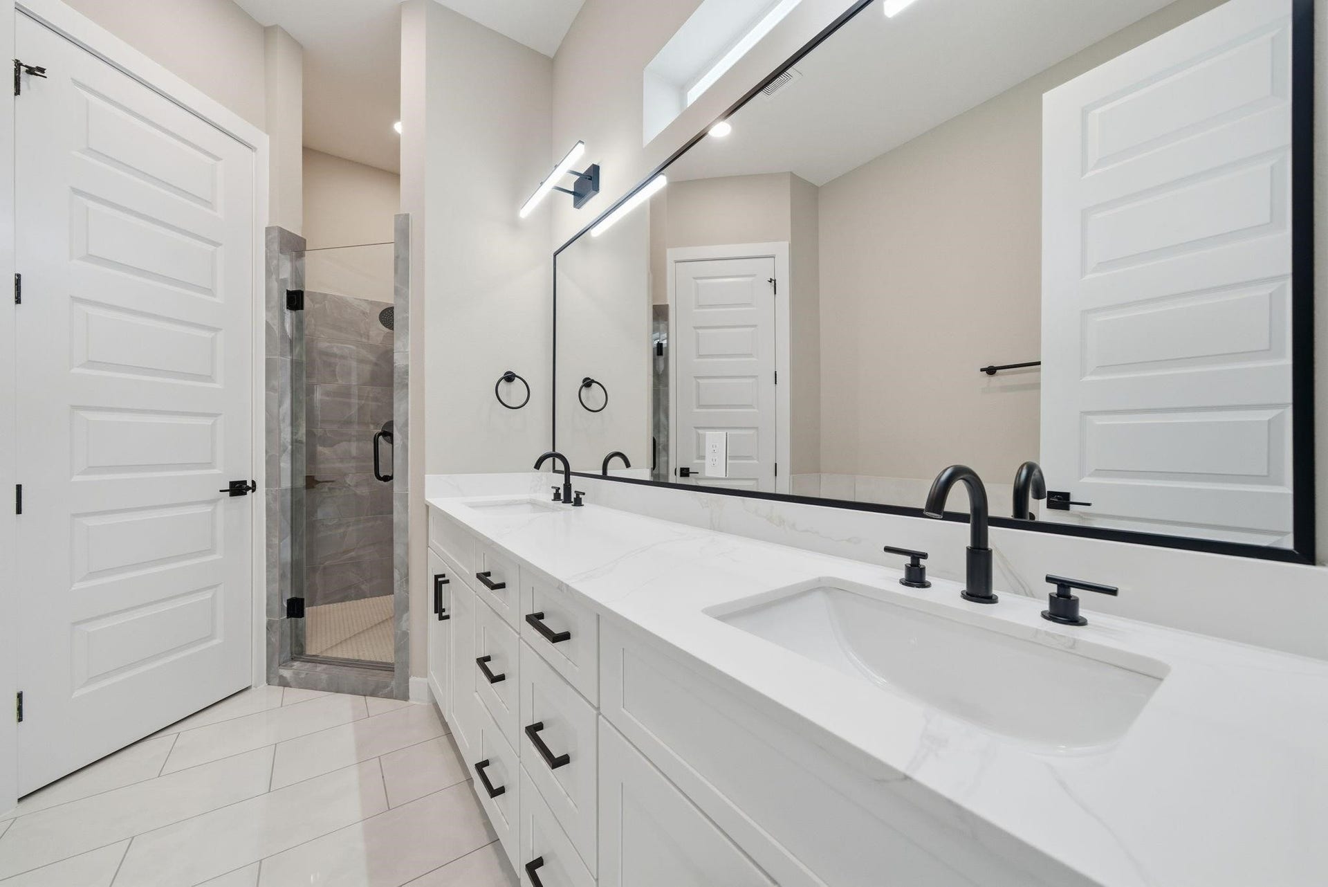 4013 Griggs Road, #F, Houston, TX 77021 Elegant bathroom featuring a spacious dual-sink vanity with modern black fixtures, a large mirror, and a stylish glass-enclosed shower.