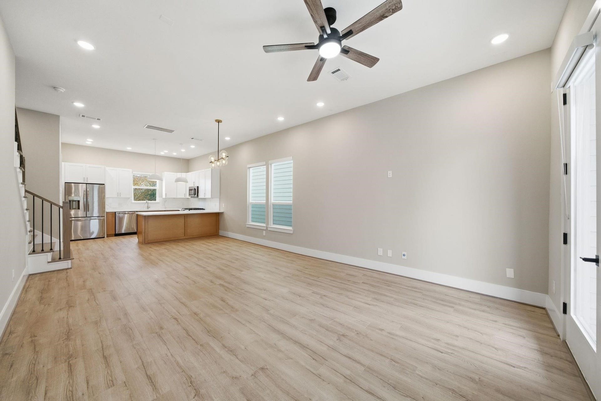 4013 Griggs Road, #F, Houston, TX 77021 Spacious open-concept living area with elegant wood flooring, modern ceiling fan, and a sleek kitchen featuring stainless steel appliances and a large island.