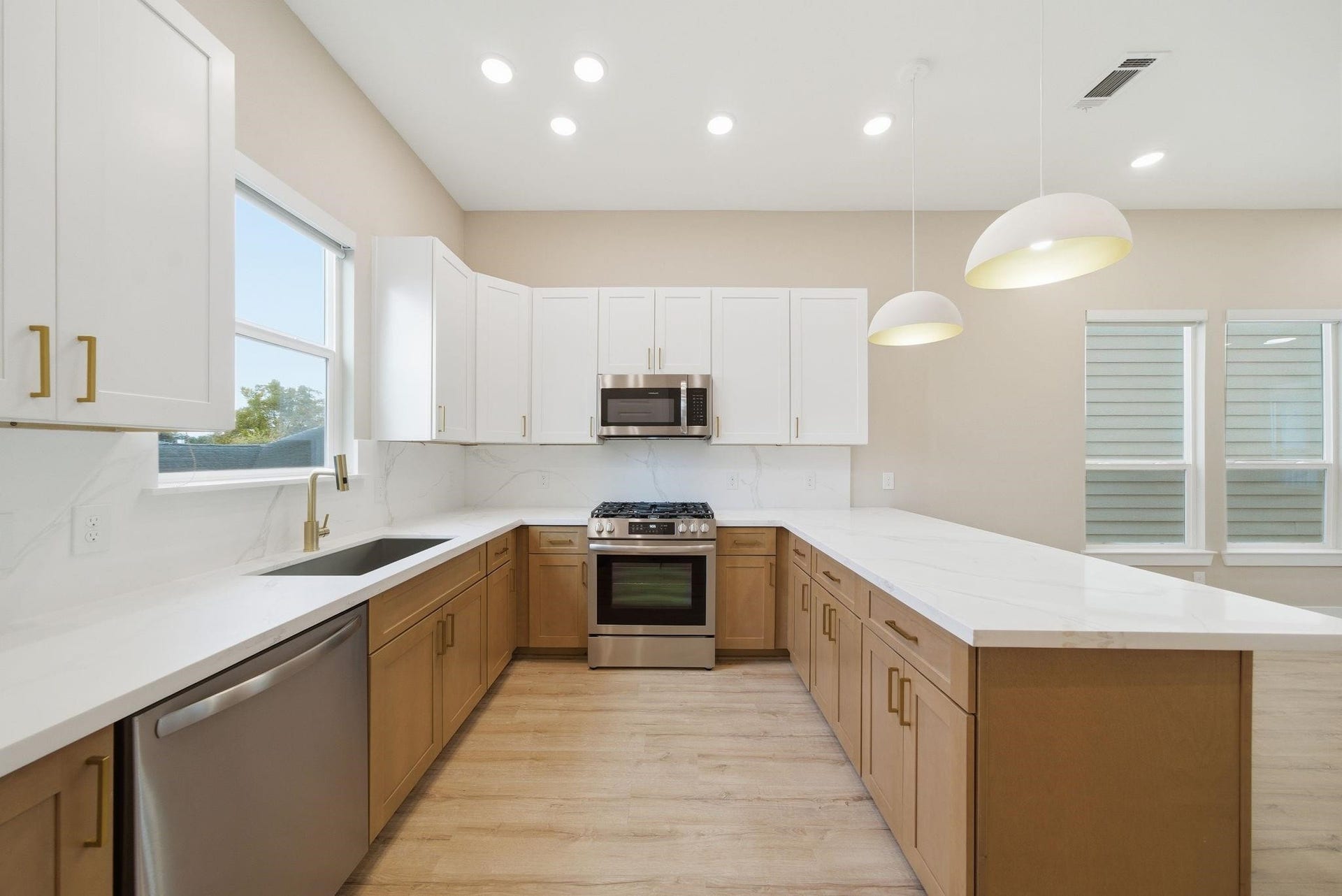 4013 Griggs Road, #F, Houston, TX 77021 Elegant kitchen featuring modern appliances, sleek white and wood cabinetry, and a spacious island with pendant lighting, perfect for entertaining.