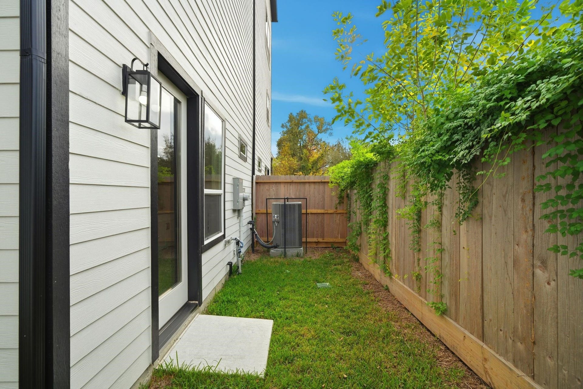 4013 Griggs Road, #F, Houston, TX 77021 Cozy side yard with a well-maintained lawn, privacy fence, and lush greenery, perfect for intimate outdoor relaxation.