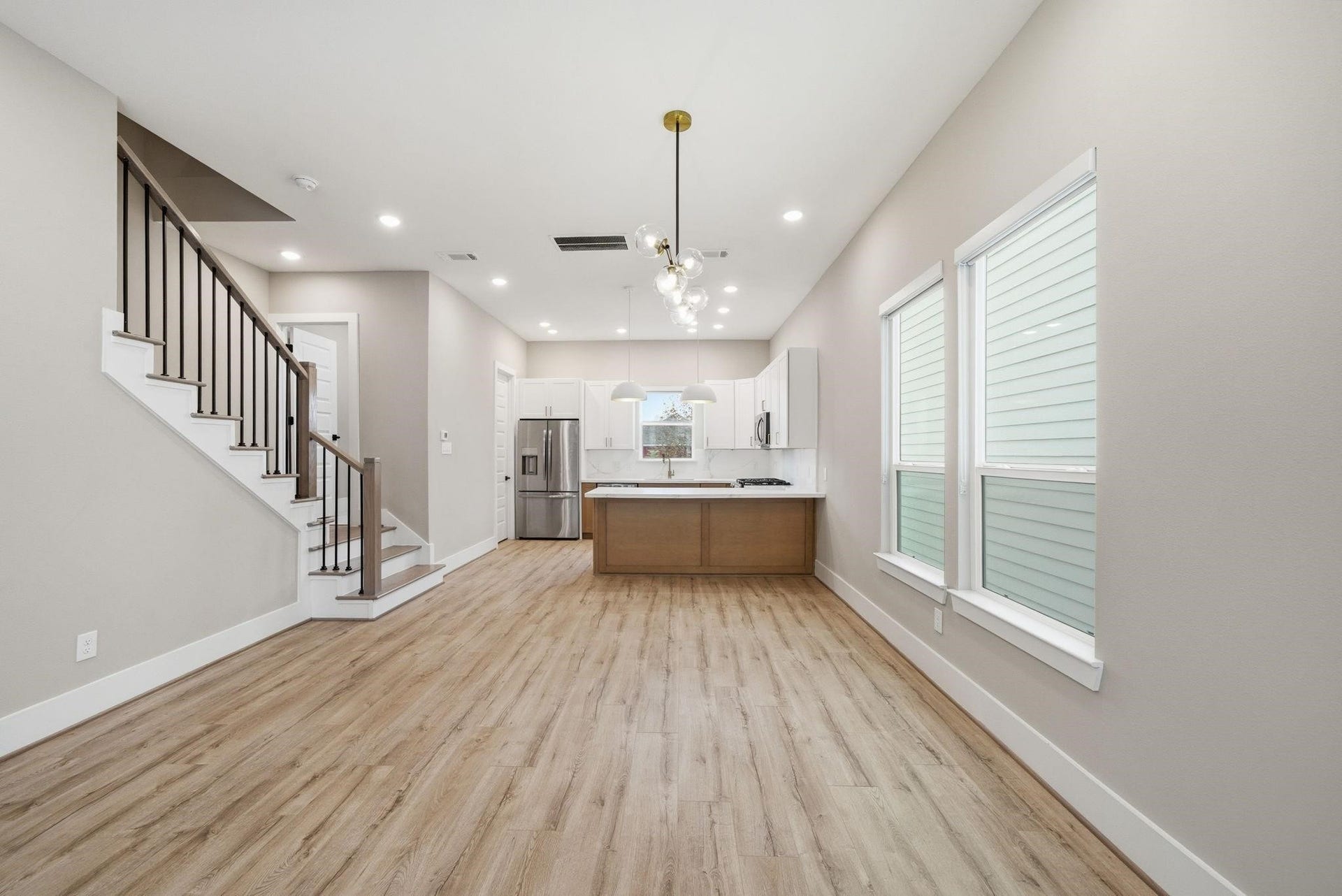 4013 Griggs Road, #F, Houston, TX 77021 Modern open-concept living area with sleek hardwood floors, featuring a stylish kitchen with stainless steel appliances and a large island. Bright natural light streams through the windows, complementing the contemporary design.