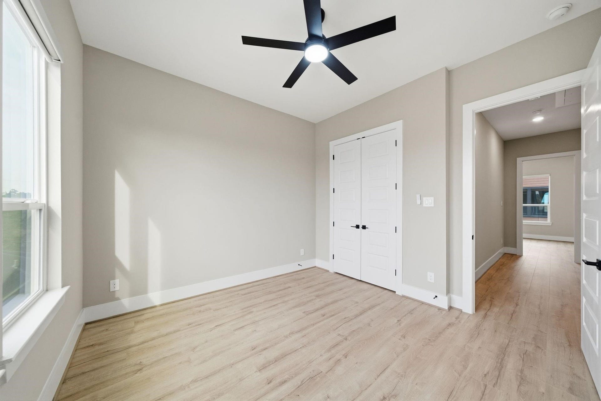 4013 Griggs Road, #F, Houston, TX 77021 Bright and airy bedroom featuring large windows, modern ceiling fan, and sleek laminate flooring, with convenient double-door closet access.