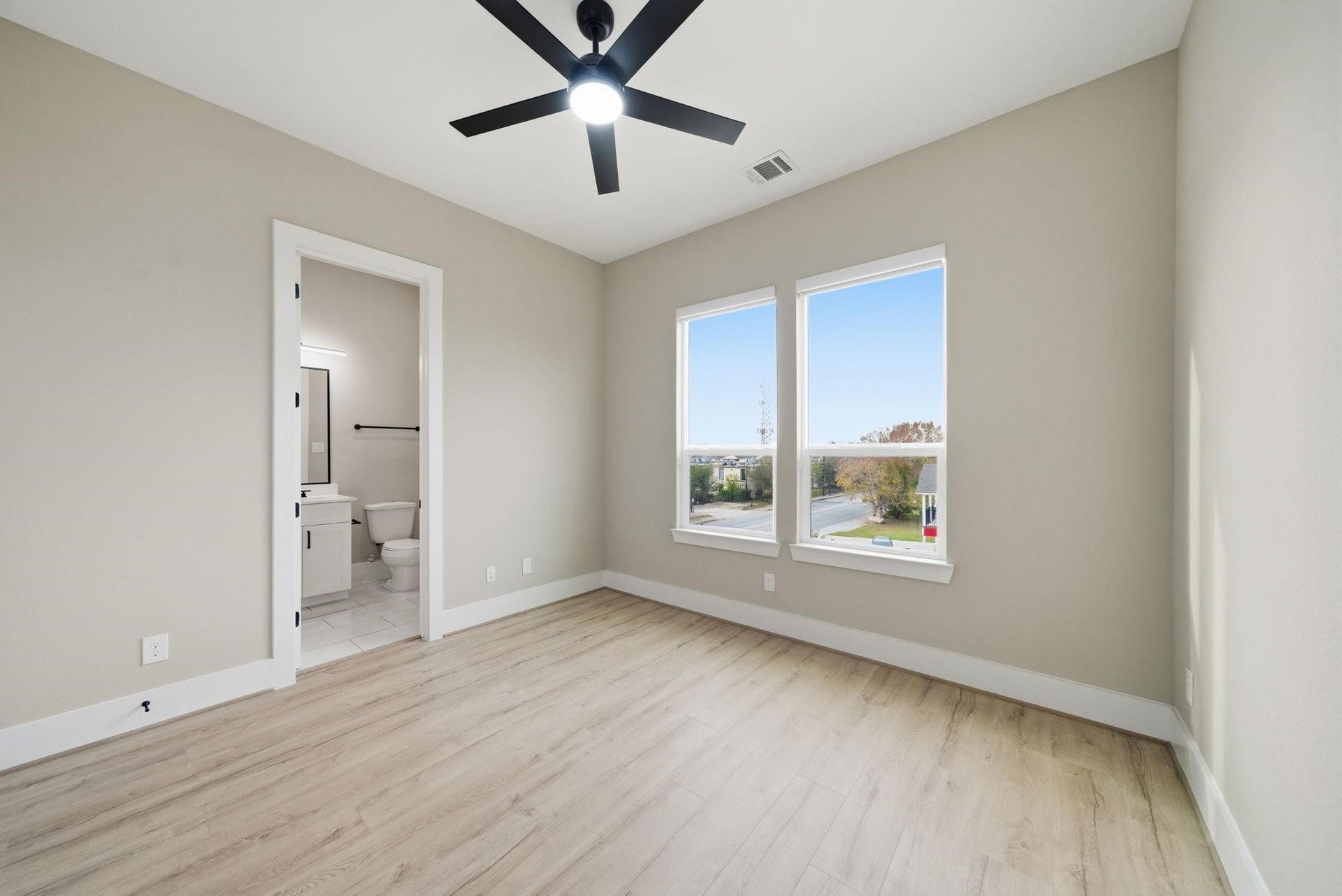 4013 Griggs Road, #F, Houston, TX 77021 Bright bedroom with large windows, light wood flooring, and an en-suite bathroom for added convenience.