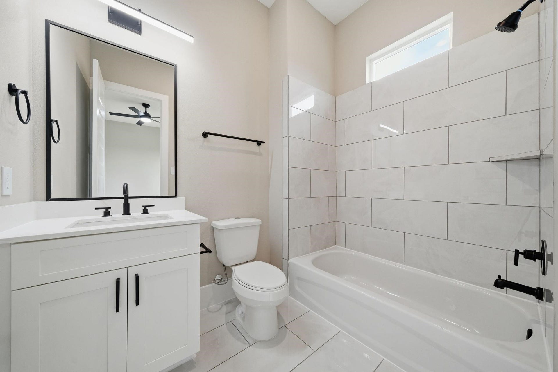4013 Griggs Road, #F, Houston, TX 77021 Elegant bathroom featuring a sleek vanity with black fixtures, a modern bathtub, and glossy white tiles for a fresh, contemporary look.