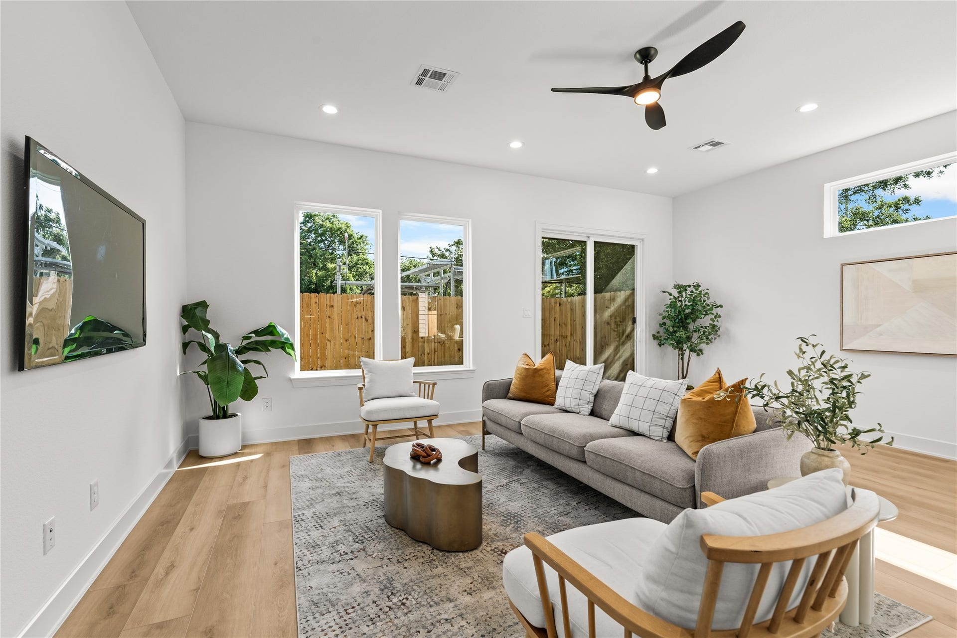 3012 & 3014 Beulah St, Houston, TX 77004 The main living room is bright and open, featuring a modern/spacious layout. Large windows look out into the backyard, providing a clean view of the horizontal wood fence and greenery while letting in plenty of natural light.