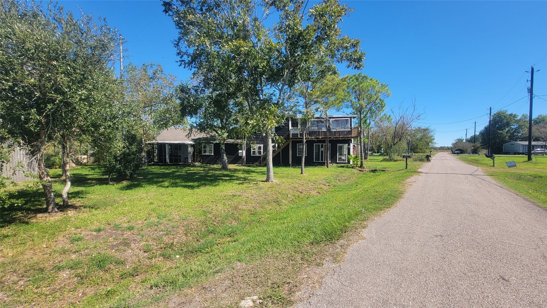12018 Sandpiper Road, Angleton, TX 77515 Charming two-story home with a rustic exterior, surrounded by trees on a spacious lot. The property is situated along a quiet, paved road in a serene neighborhood, offering ample outdoor space and privacy.