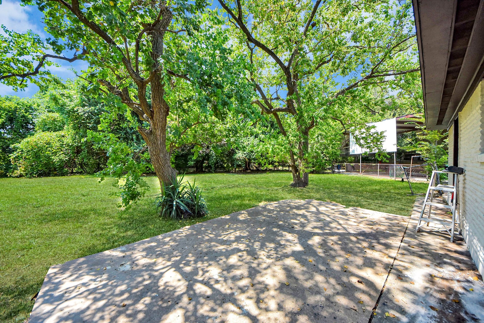602 Gammon Drive, Houston, TX 77022 A spacious backyard with lush green grass and mature trees offers ample shade and a serene atmosphere, perfect for outdoor relaxation or entertaining.