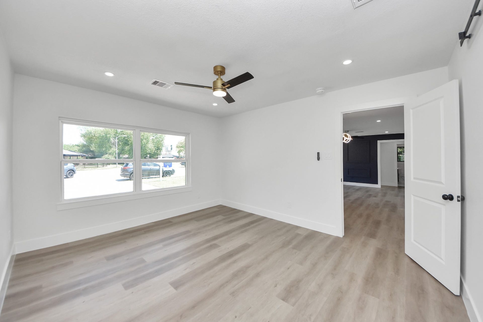 602 Gammon Drive, Houston, TX 77022 Bright and airy room featuring large windows, sleek flooring, and a modern ceiling fan, offering a seamless transition into the adjacent space.