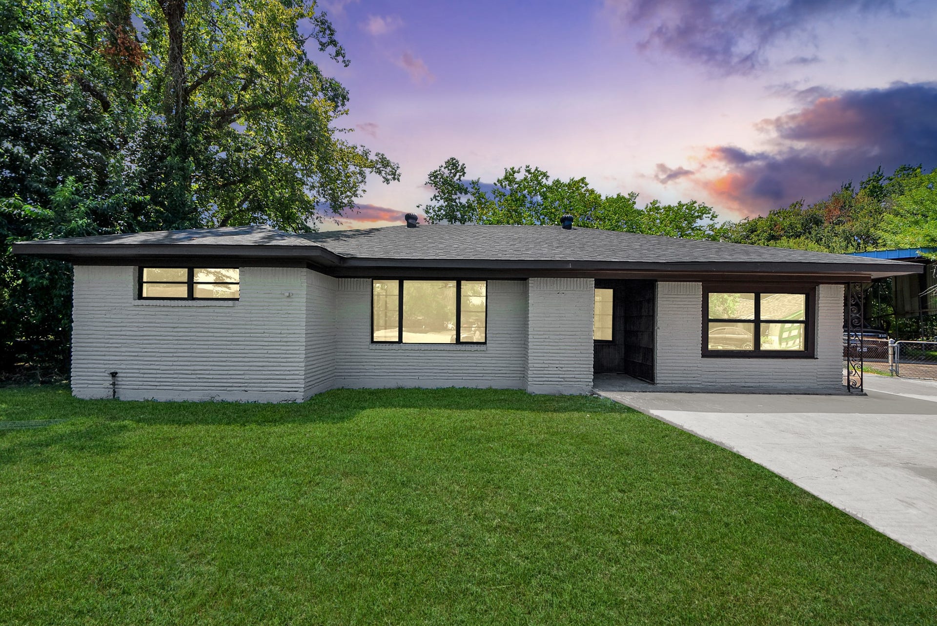 602 Gammon Drive, Houston, TX 77022 Charming single-story home with a fresh white brick exterior, large windows, and a spacious front yard framed by mature trees.