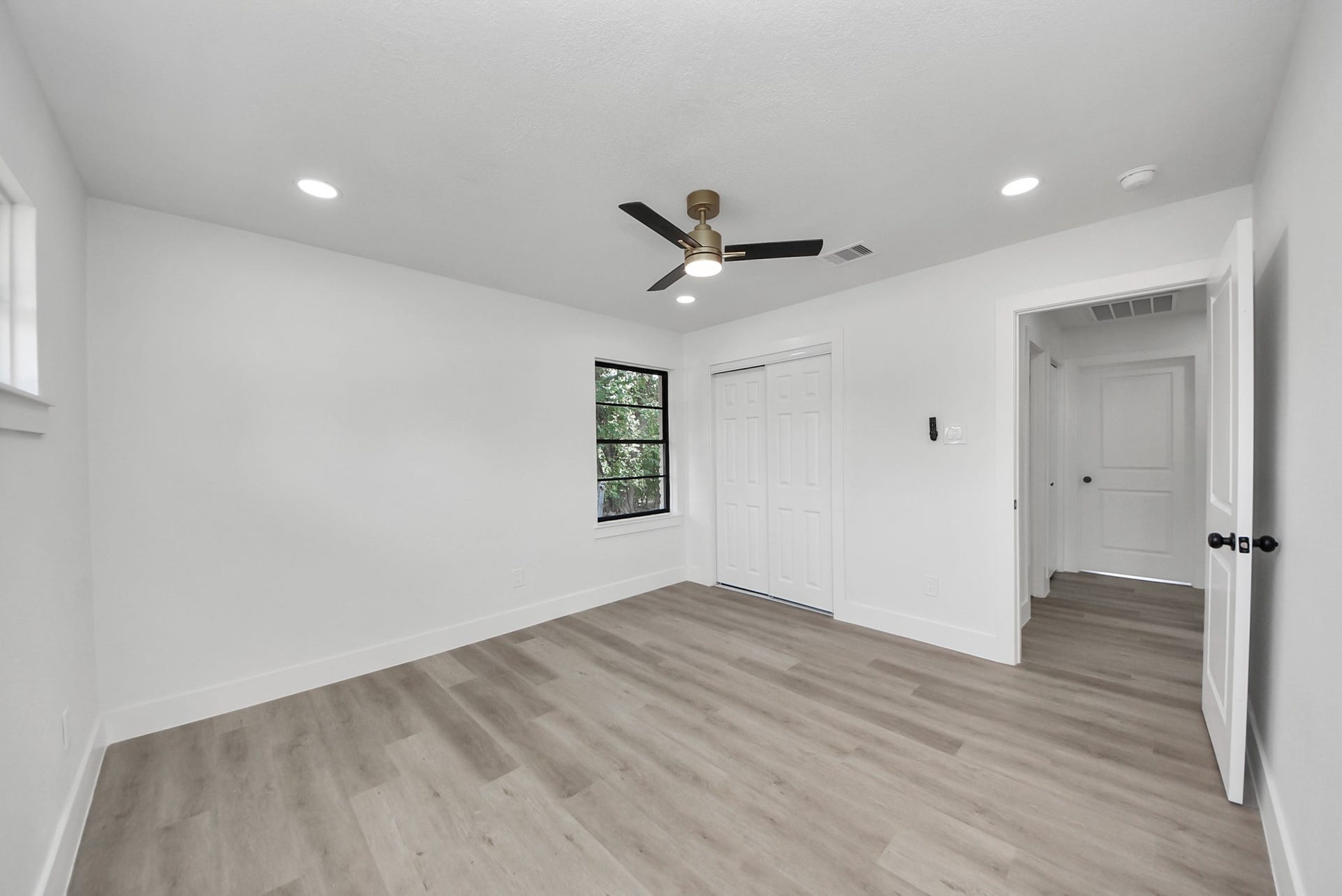 602 Gammon Drive, Houston, TX 77022 Spacious and bright room featuring modern recessed lighting, sleek ceiling fan, and elegant wood flooring, with ample closet space and a large window for natural light.
