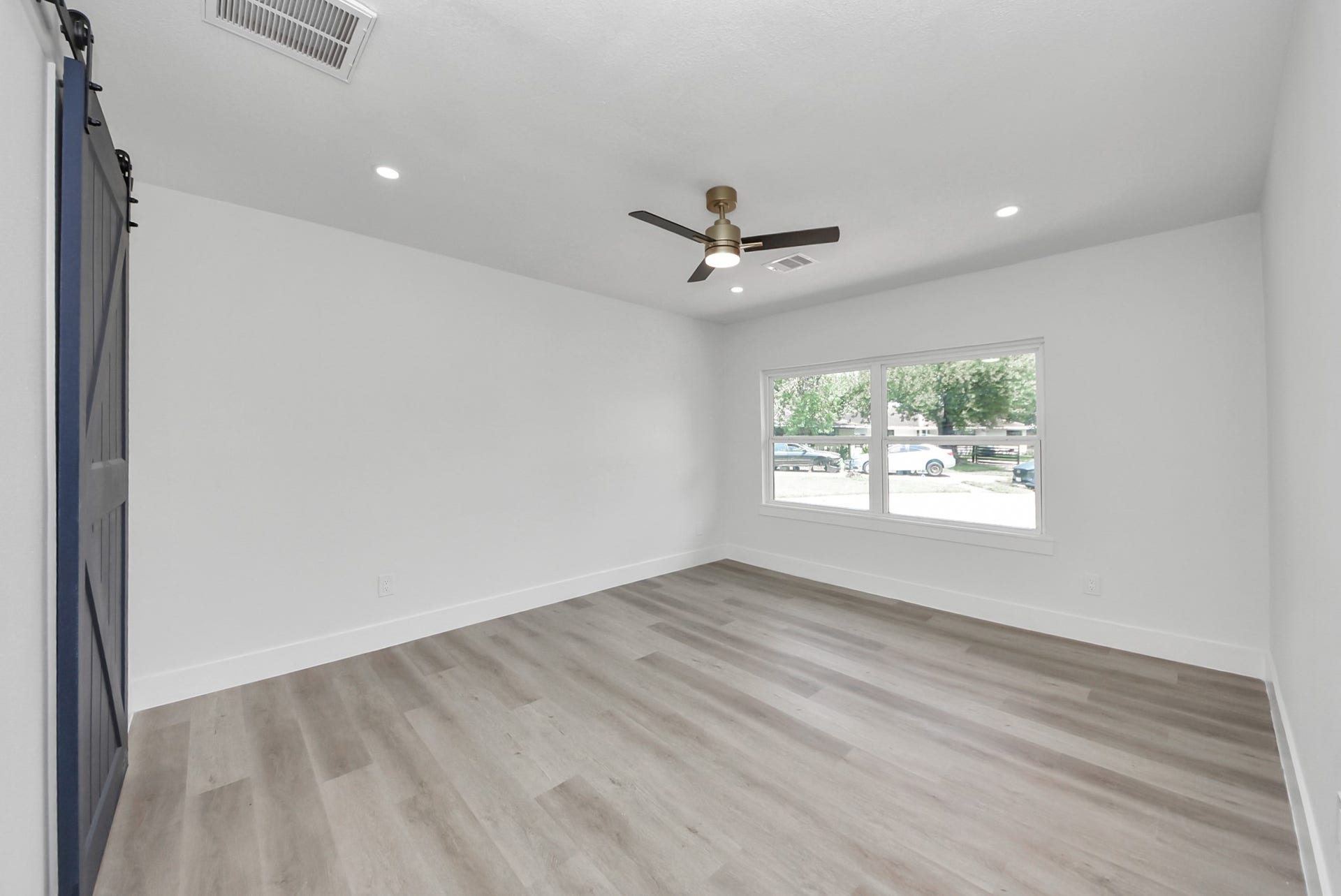 602 Gammon Drive, Houston, TX 77022 Bright, spacious room featuring sleek hardwood floors, a modern ceiling fan, and large windows that offer plenty of natural light.
