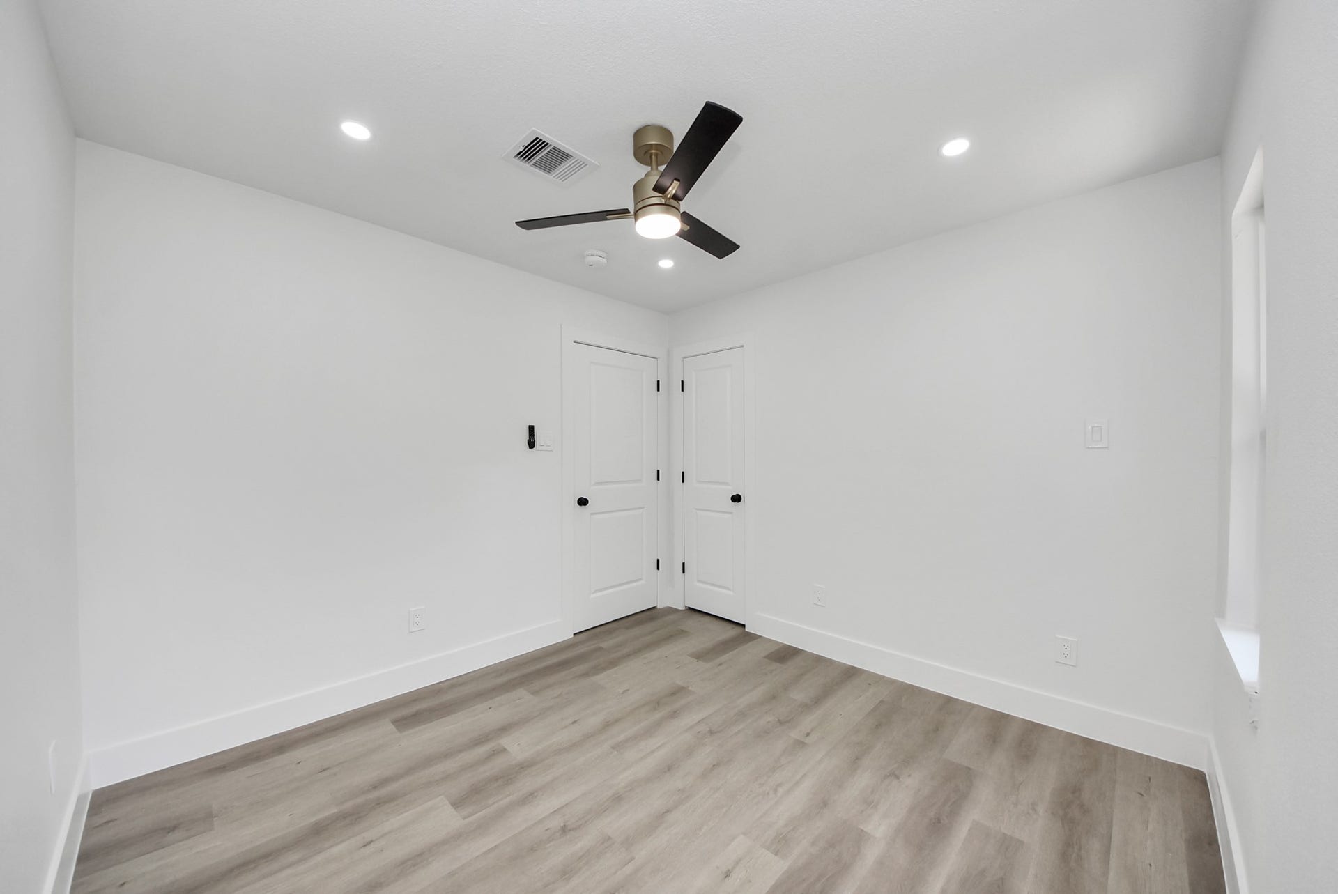 602 Gammon Drive, Houston, TX 77022 Bright, minimalist bedroom featuring sleek wood flooring, fresh white walls, and a modern ceiling fan, offering a serene and contemporary space.