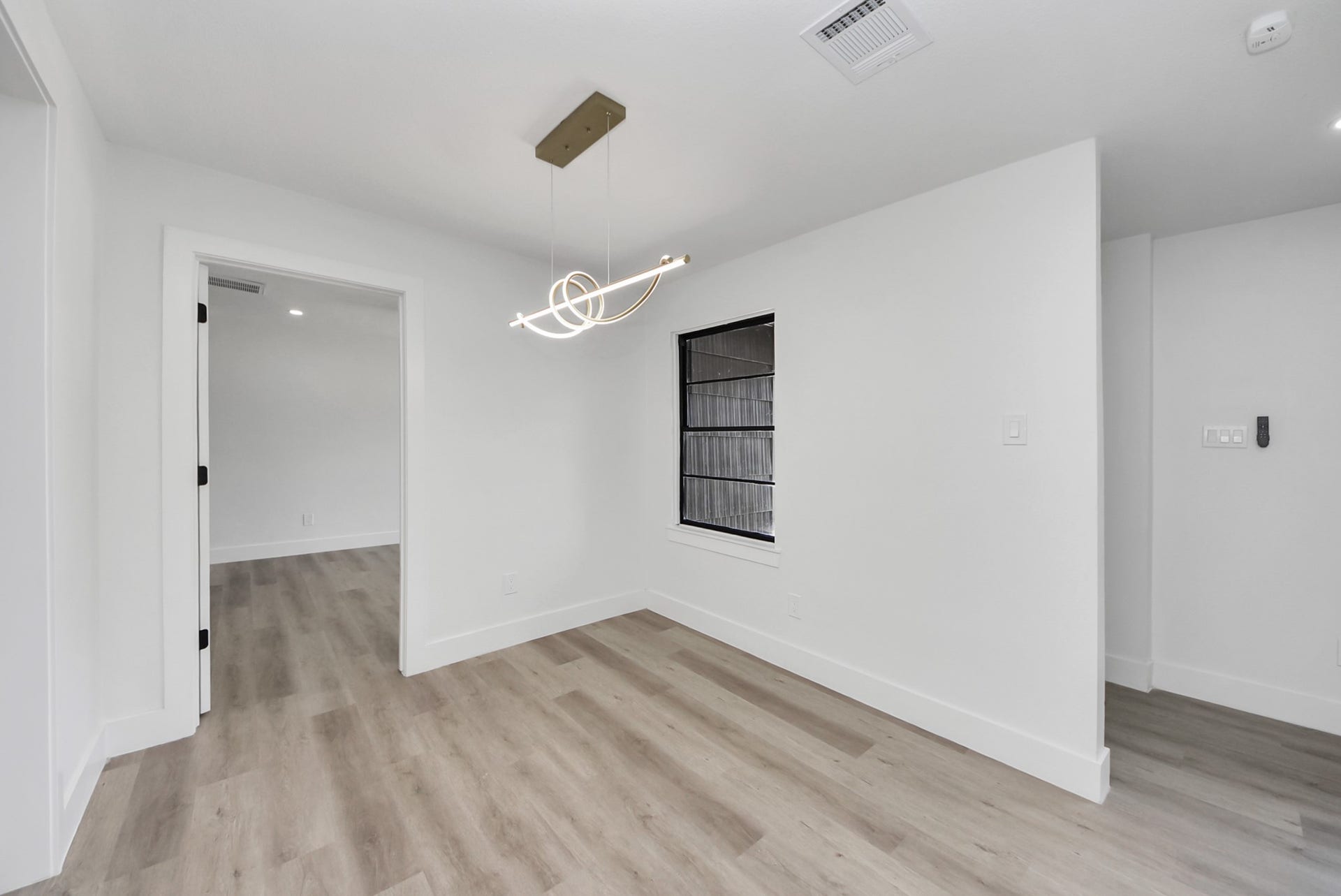 602 Gammon Drive, Houston, TX 77022 Bright and modern room featuring sleek wood flooring, a contemporary light fixture, and a large window, offering a versatile space for dining or lounging.