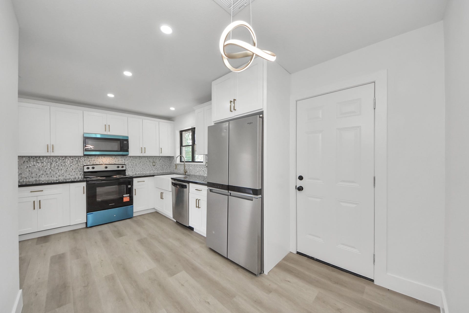 602 Gammon Drive, Houston, TX 77022 Modern kitchen with sleek stainless steel appliances, elegant white cabinetry, and a stylish geometric backsplash.