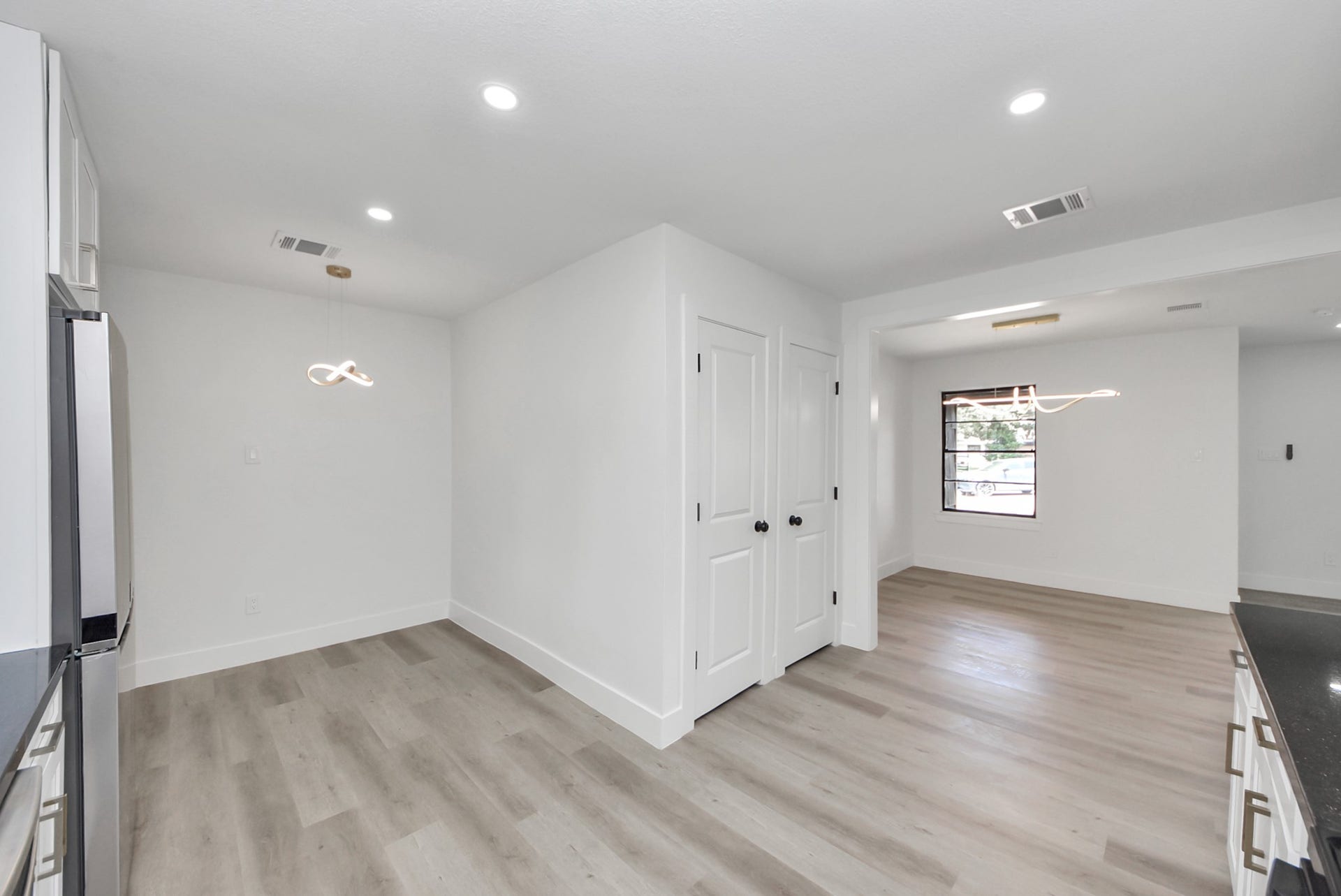 602 Gammon Drive, Houston, TX 77022 Bright and modern open-concept space featuring sleek hardwood floors, recessed lighting, and a contemporary light fixture. The area is versatile, leading to a window that offers natural light and a view outside.