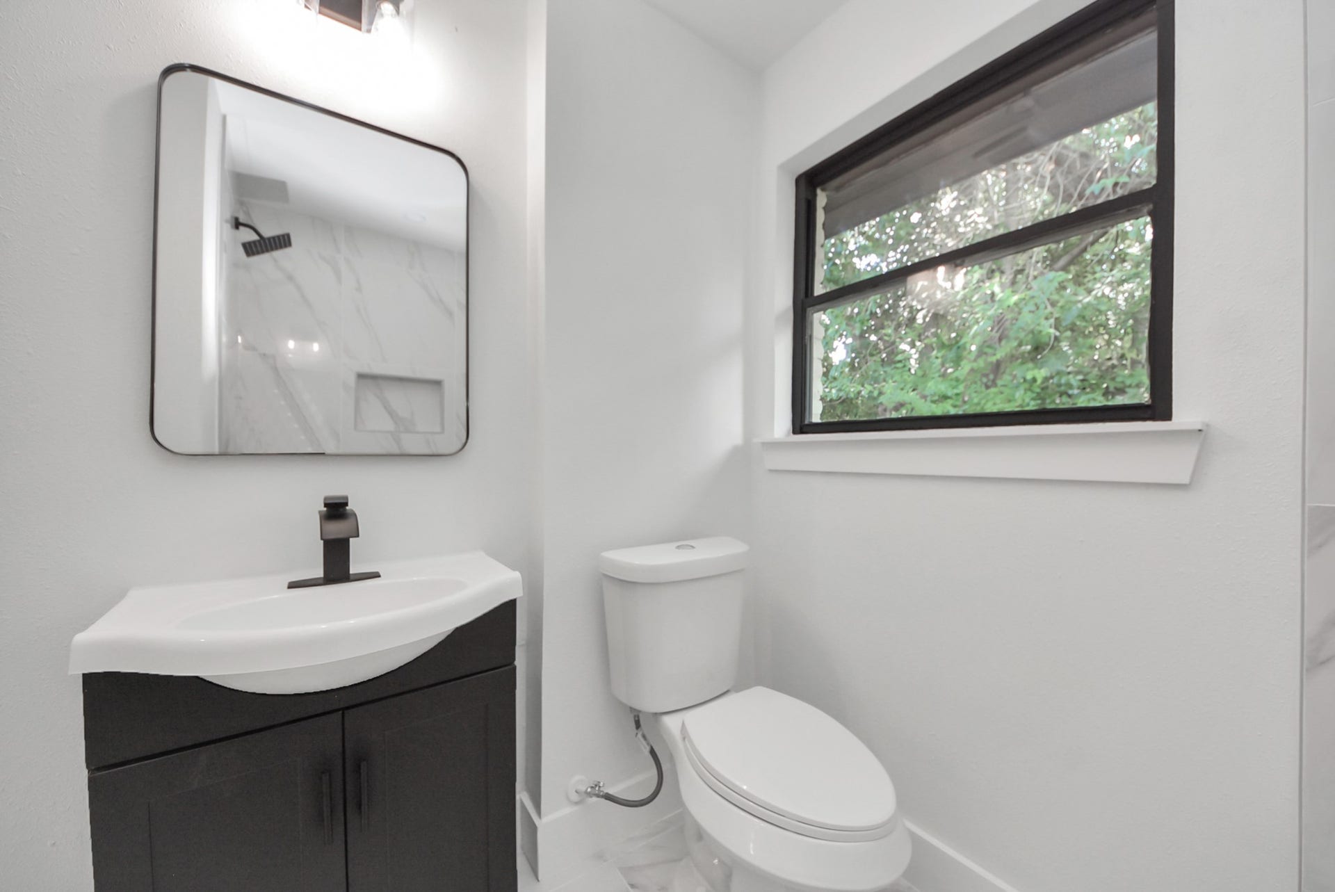 602 Gammon Drive, Houston, TX 77022 Bright, modern bathroom featuring a sleek vanity, stylish fixtures, and a large window with a serene view.