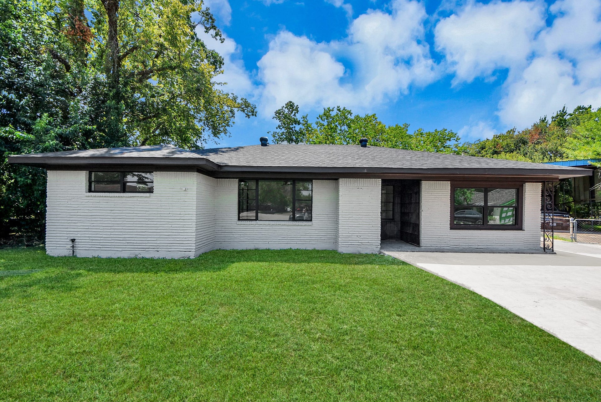 602 Gammon Drive, Houston, TX 77022 Charming single-story home with a modern exterior, featuring a sleek white brick facade and large windows for abundant natural light, set on a lush green lawn.
