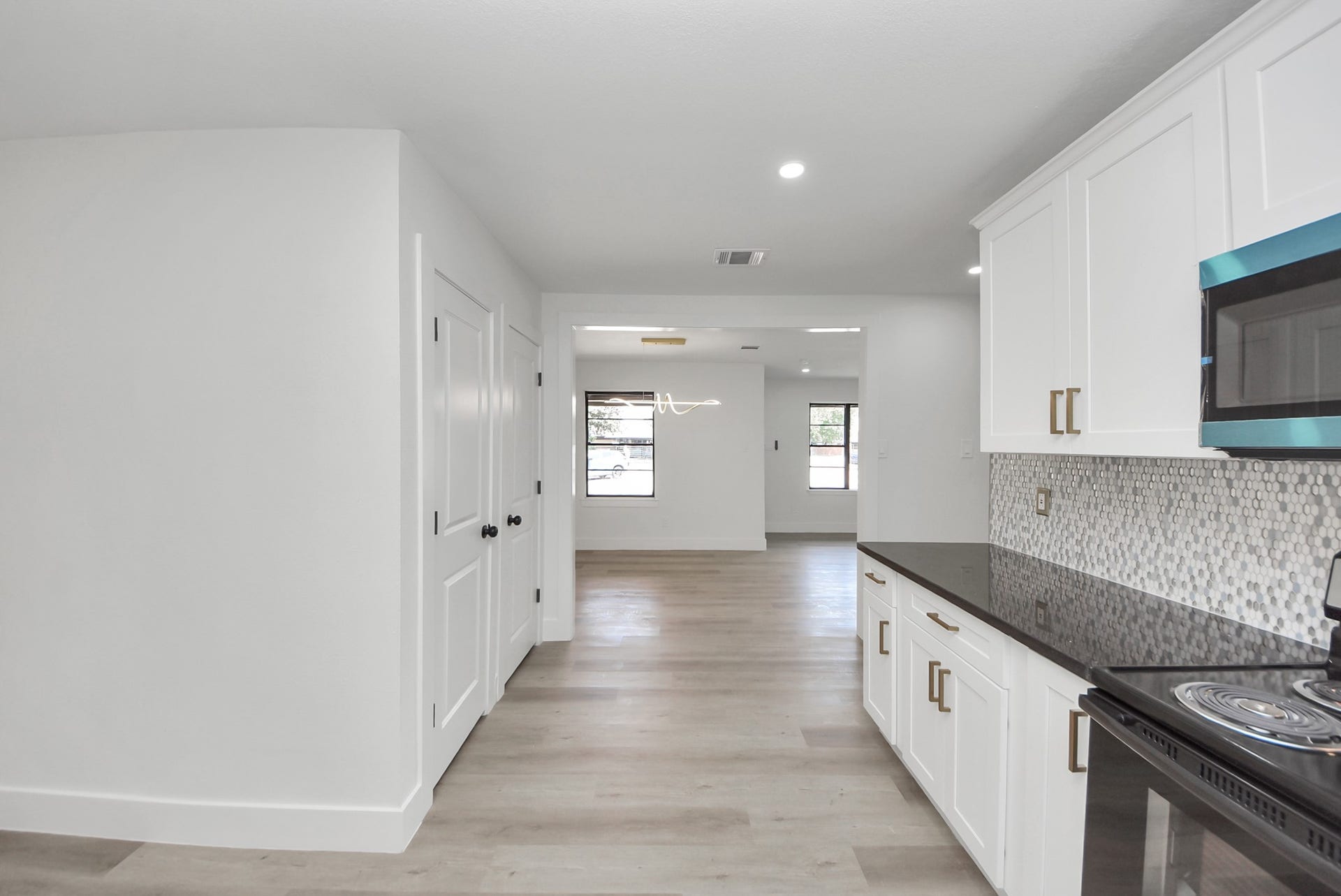 602 Gammon Drive, Houston, TX 77022 Modern kitchen with sleek white cabinetry, black countertops, and stylish backsplash leading into an open, well-lit living space.