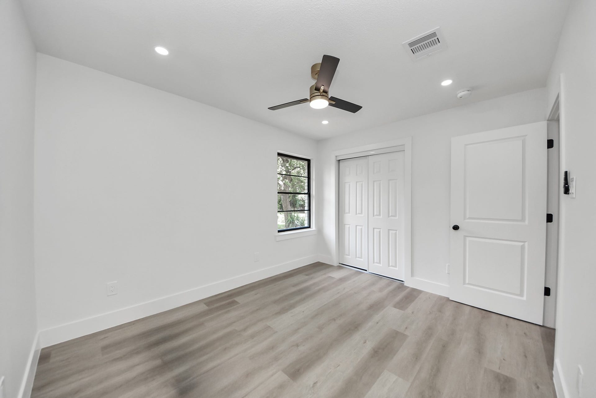 602 Gammon Drive, Houston, TX 77022 Bright and airy bedroom featuring sleek laminate flooring, a modern ceiling fan, and ample closet space, accentuated by soft recessed lighting.