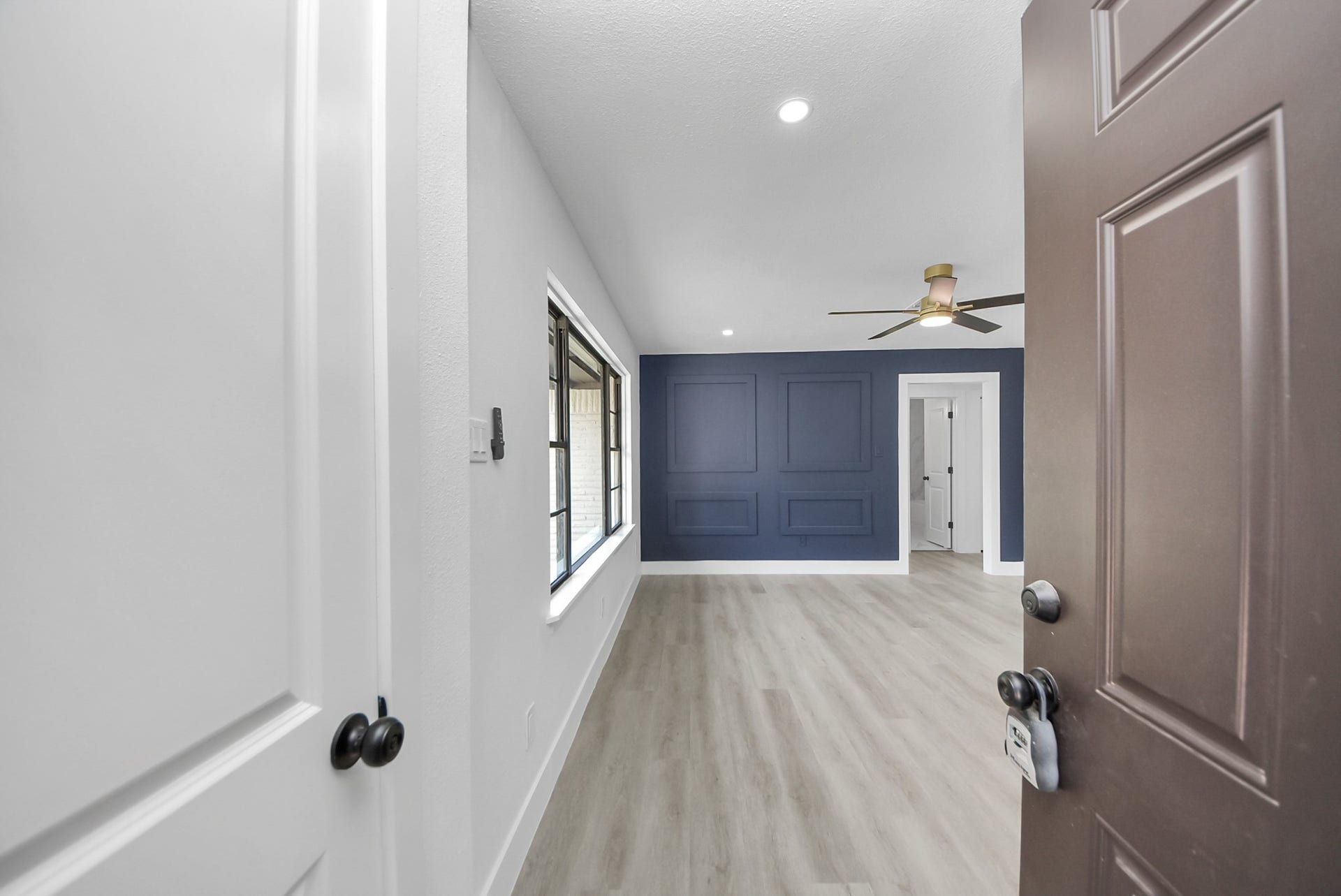 602 Gammon Drive, Houston, TX 77022 Bright and inviting room featuring a stylish blue accent wall, modern ceiling fan, and sleek wood flooring, offering a perfect blend of comfort and contemporary design.