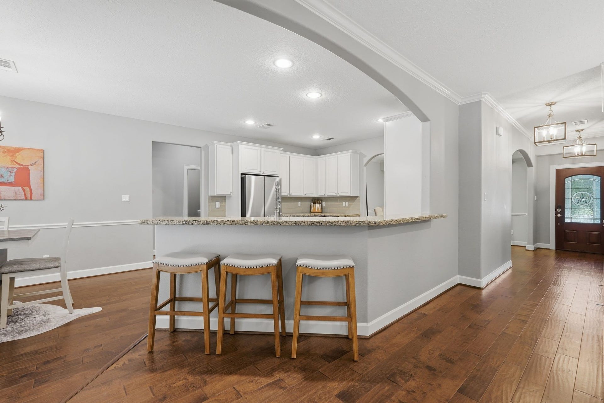 Open concept white kitchen, stainless appliances, granite countertops, and walk-in pantry.