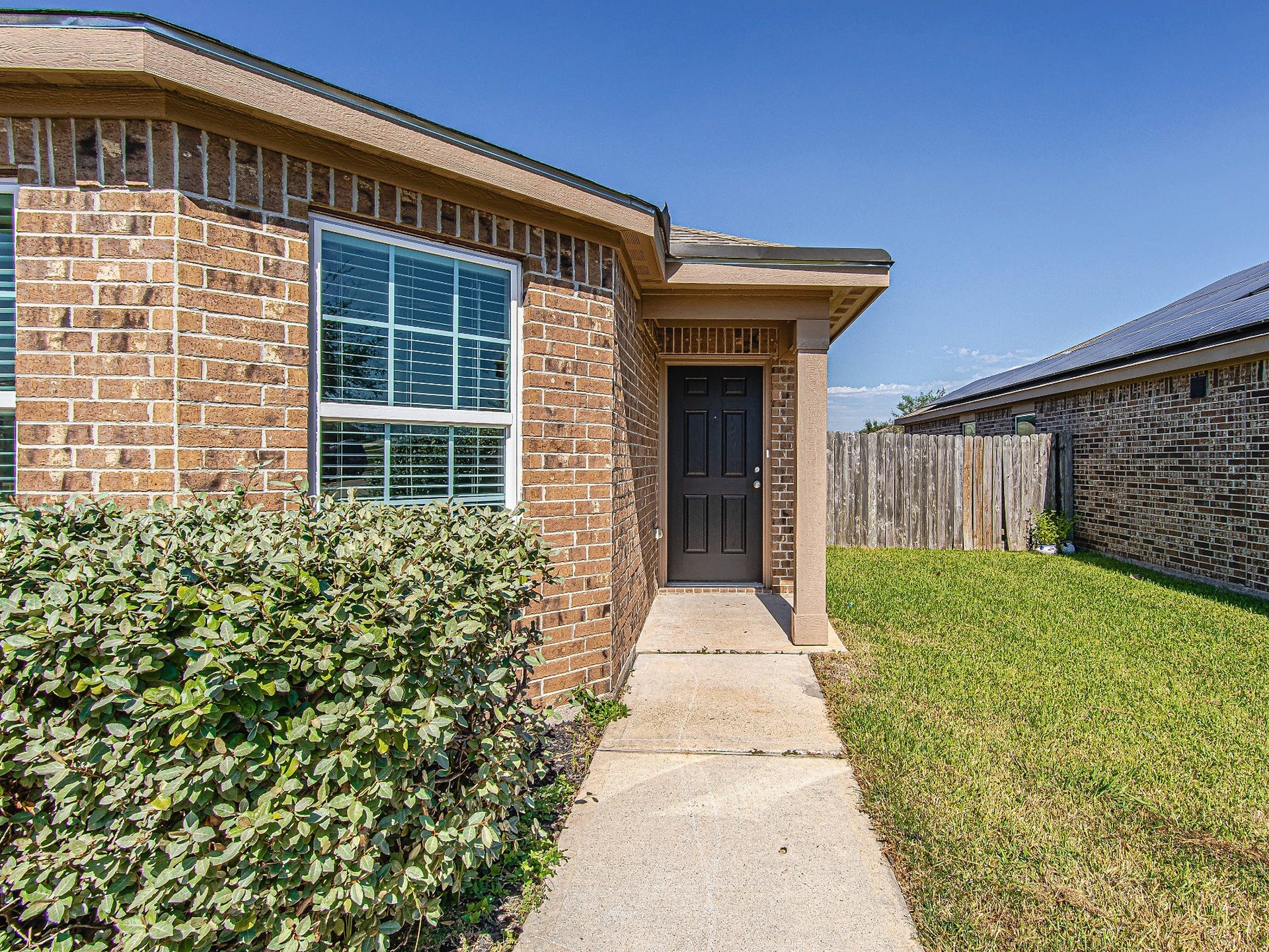 1223 Emerald Stone Drive, Rosharon, TX 77583 A covered front entry welcomes guests, with a concrete walkway and established shrubs framing the approach.