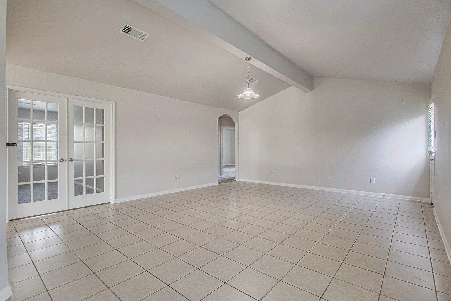 1223 Emerald Stone Drive, Rosharon, TX 77583 The living room features tile flooring, a ceiling fan, and backyard access, offering a comfortable space for everyday living.