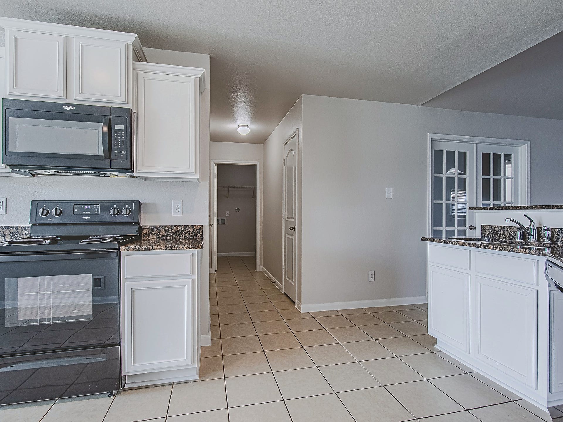 1223 Emerald Stone Drive, Rosharon, TX 77583 A range and built-in microwave pair with granite work surfaces and upper and lower cabinets to create a practical cooking space.