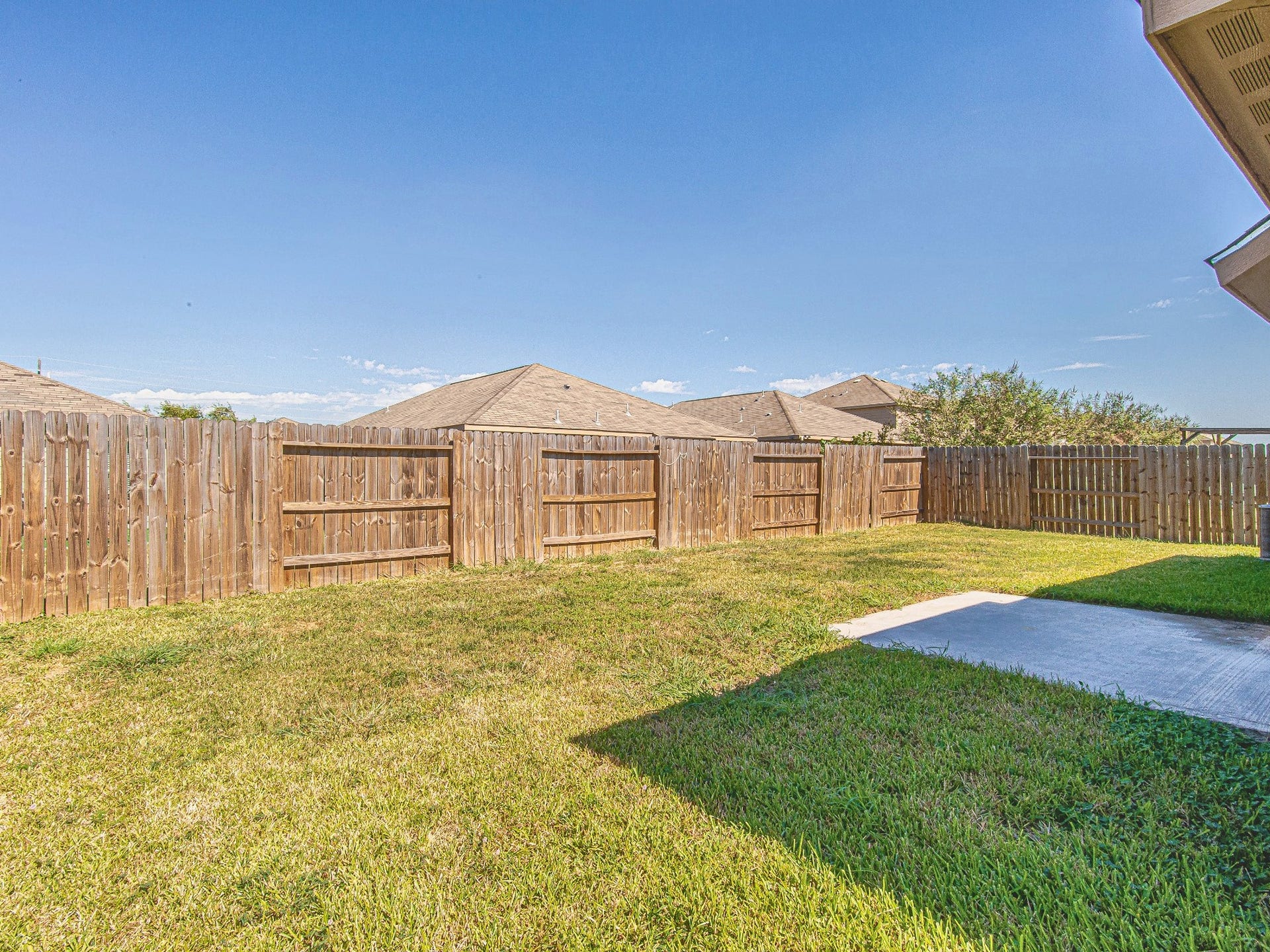 1223 Emerald Stone Drive, Rosharon, TX 77583 The fully fenced backyard features an open lawn and a concrete patio, providing space for outdoor seating and weekend gatherings.