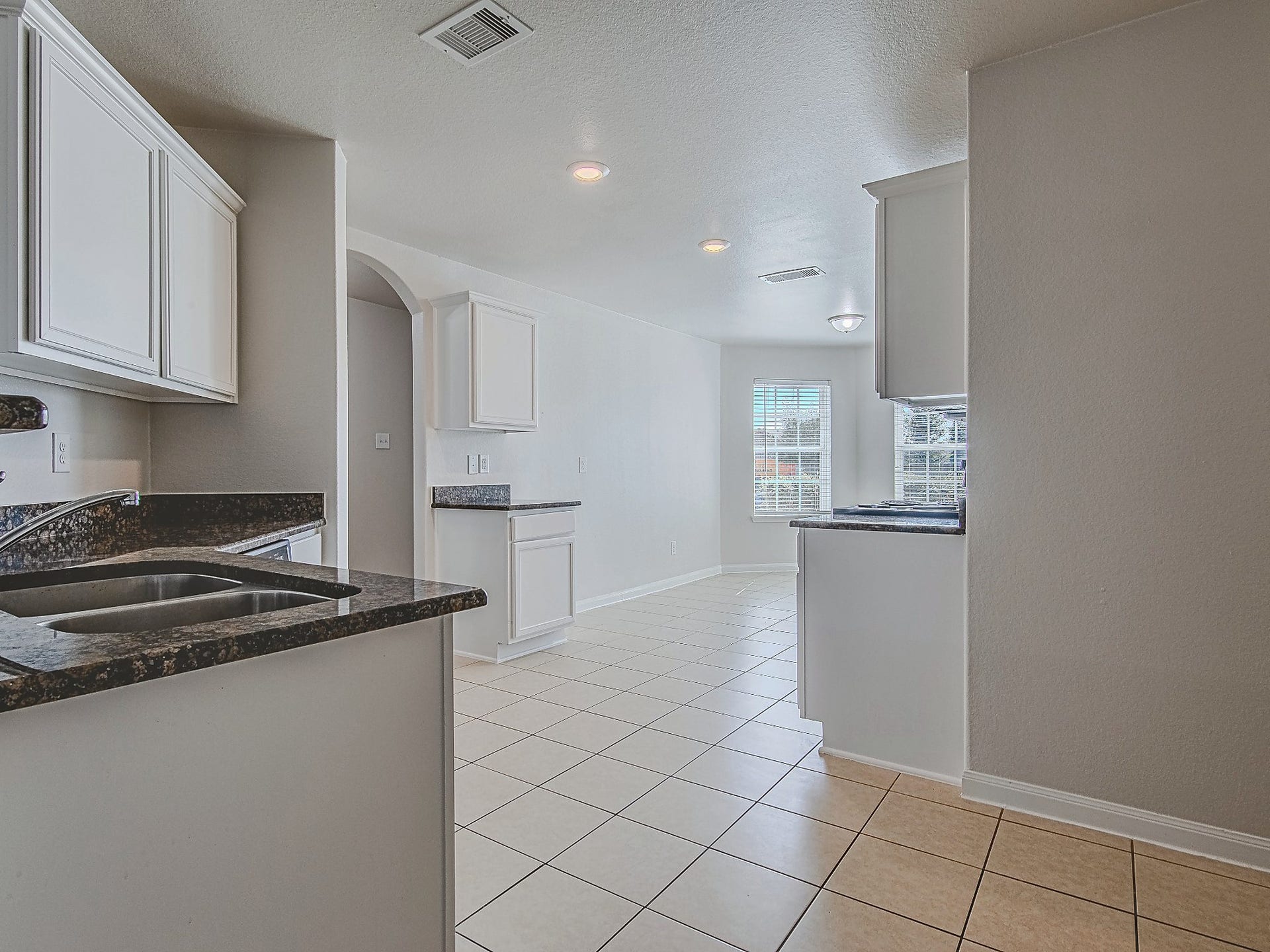 1223 Emerald Stone Drive, Rosharon, TX 77583 The kitchen features granite countertops, white cabinetry, and tile flooring, with a bright dining nook just beyond.