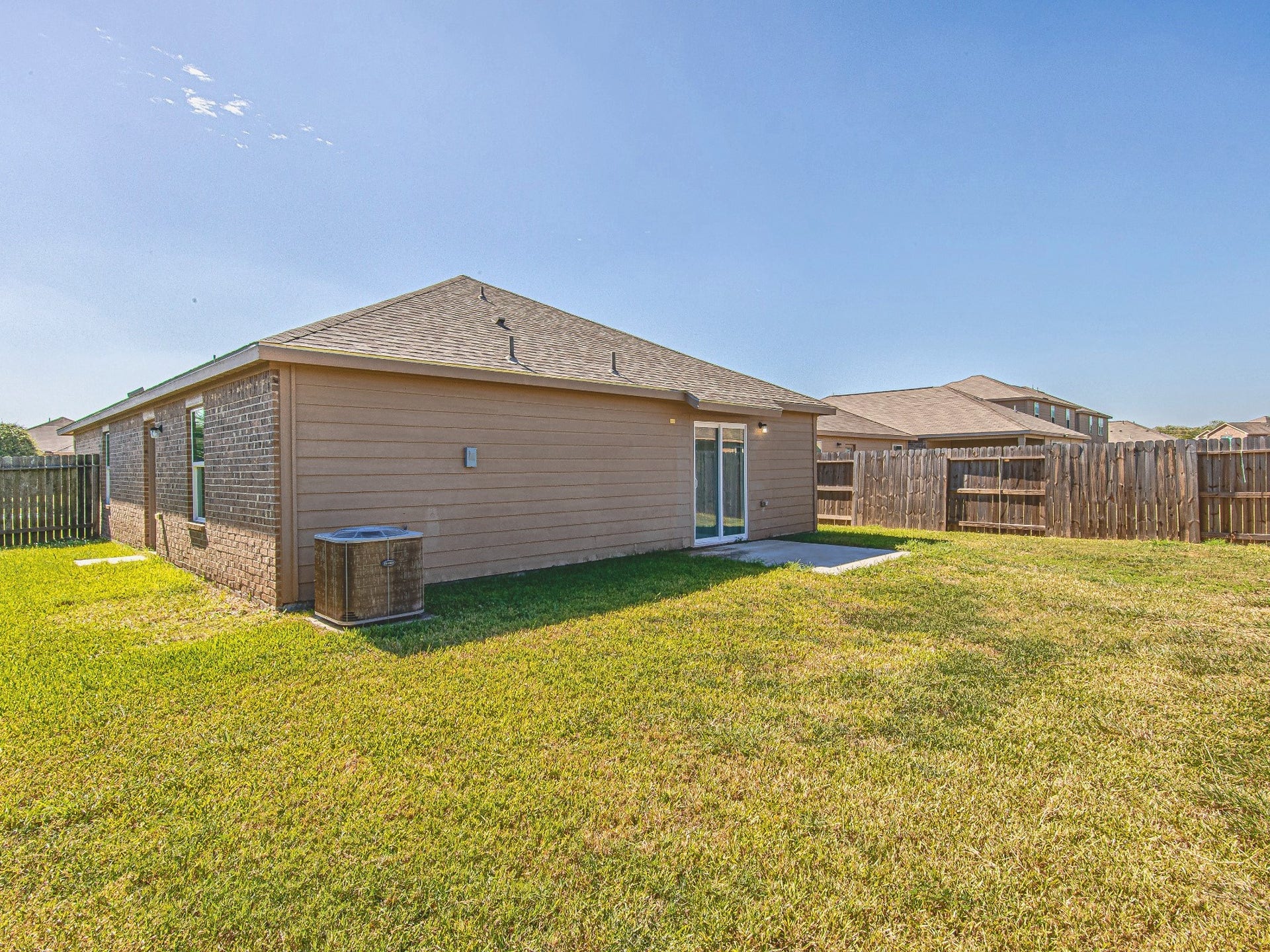 1223 Emerald Stone Drive, Rosharon, TX 77583 A wide backyard view highlights the grassy outdoor space and wood privacy fencing surrounding the property.
