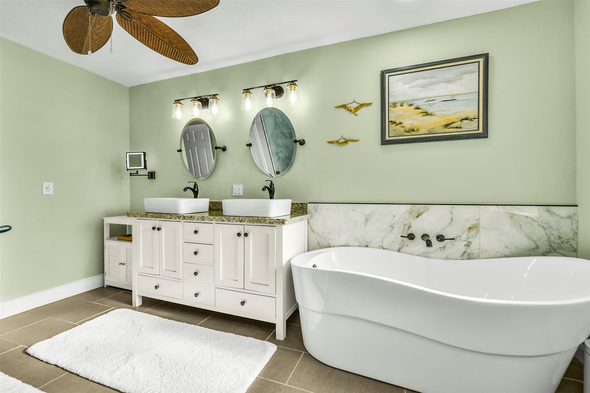 19611 Suncove Lane, Humble, TX 77346 Let the day unwind with a long soak. A sculptural freestanding tub anchors this inviting bath, complemented by soft green walls, a patterned tile backdrop and a dual-sink vanity with convenient drawer storage.