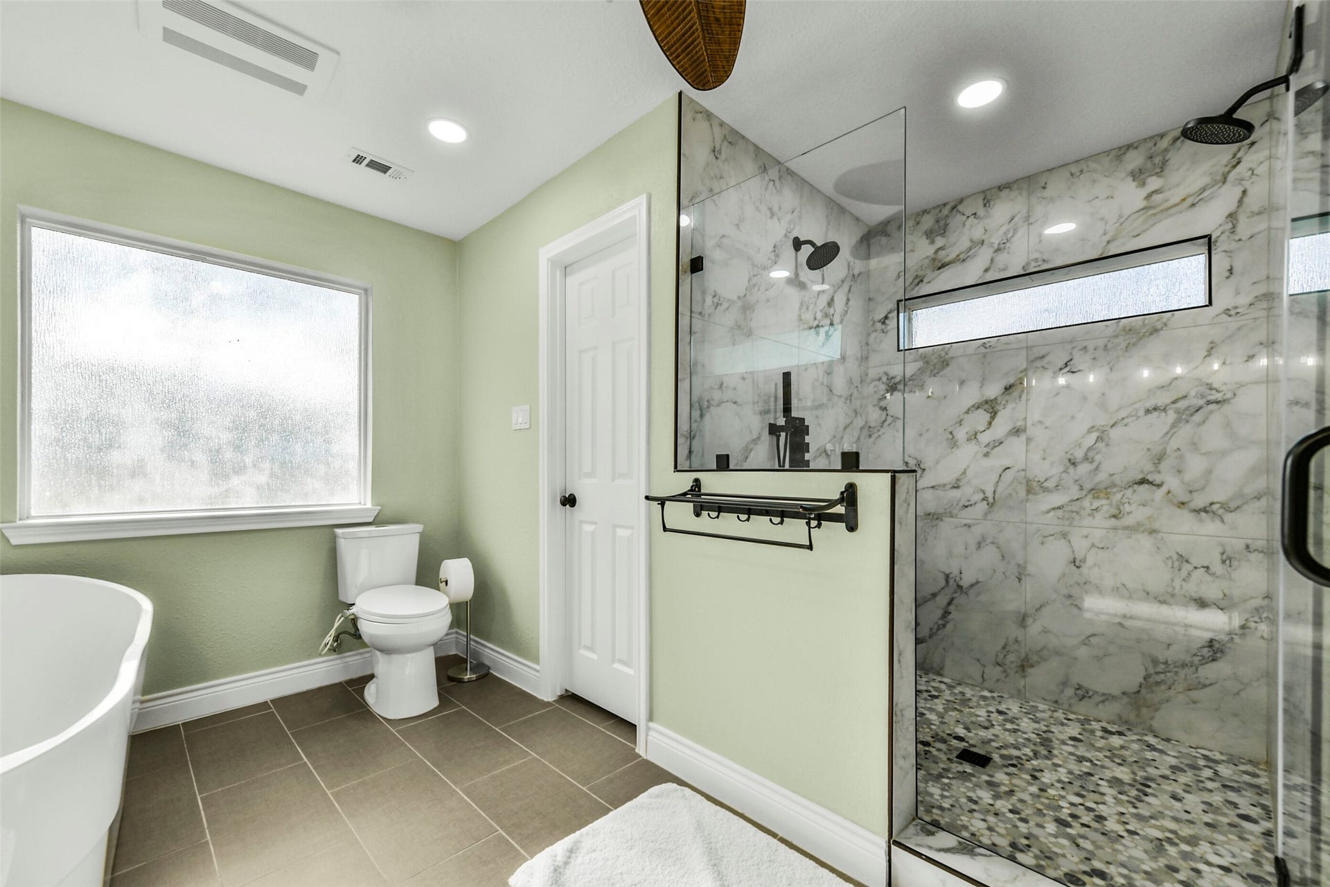 19611 Suncove Lane, Humble, TX 77346 A shower worth slowing down for. Marble-look tile, a pebble-style floor and contrasting dark fixtures create a striking combination, while the glass enclosure and high window keep the space feeling bright and open.