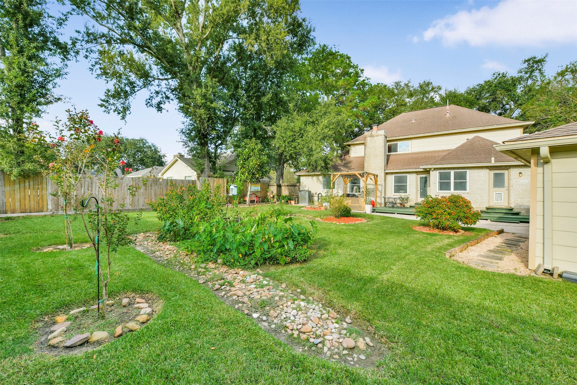 19611 Suncove Lane, Humble, TX 77346 A backyard with room to roam and reasons to slow down. Mature trees, garden beds and a winding stone-lined landscape feature create an inviting setting for tending plants, enjoying the sunshine or simply taking in the view.