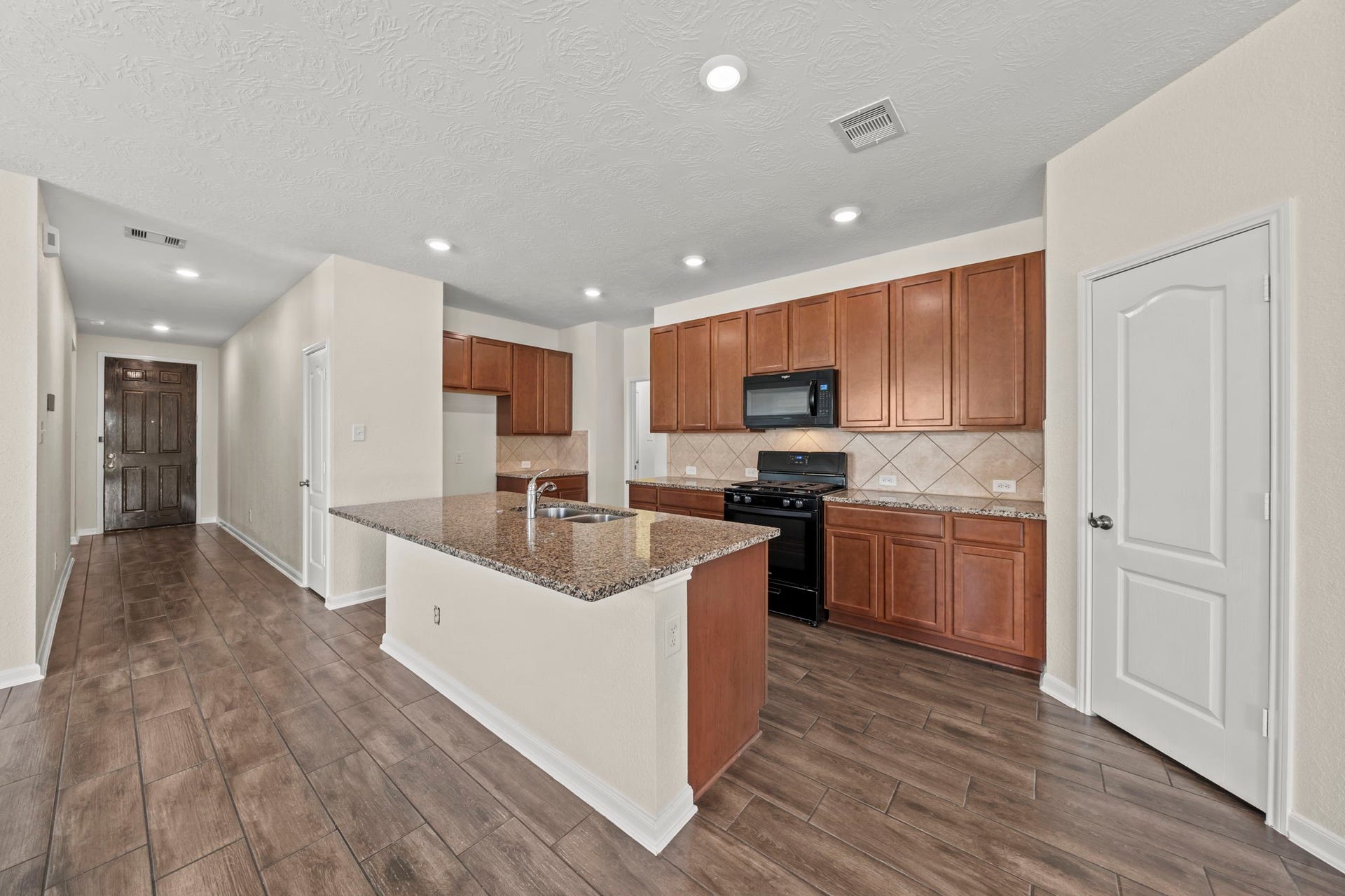 8908 Bear Mountain Court, Magnolia, TX 77354 Designed for easy cooking and entertaining, this kitchen boasts rich cabinetry, granite countertops, and a central island.