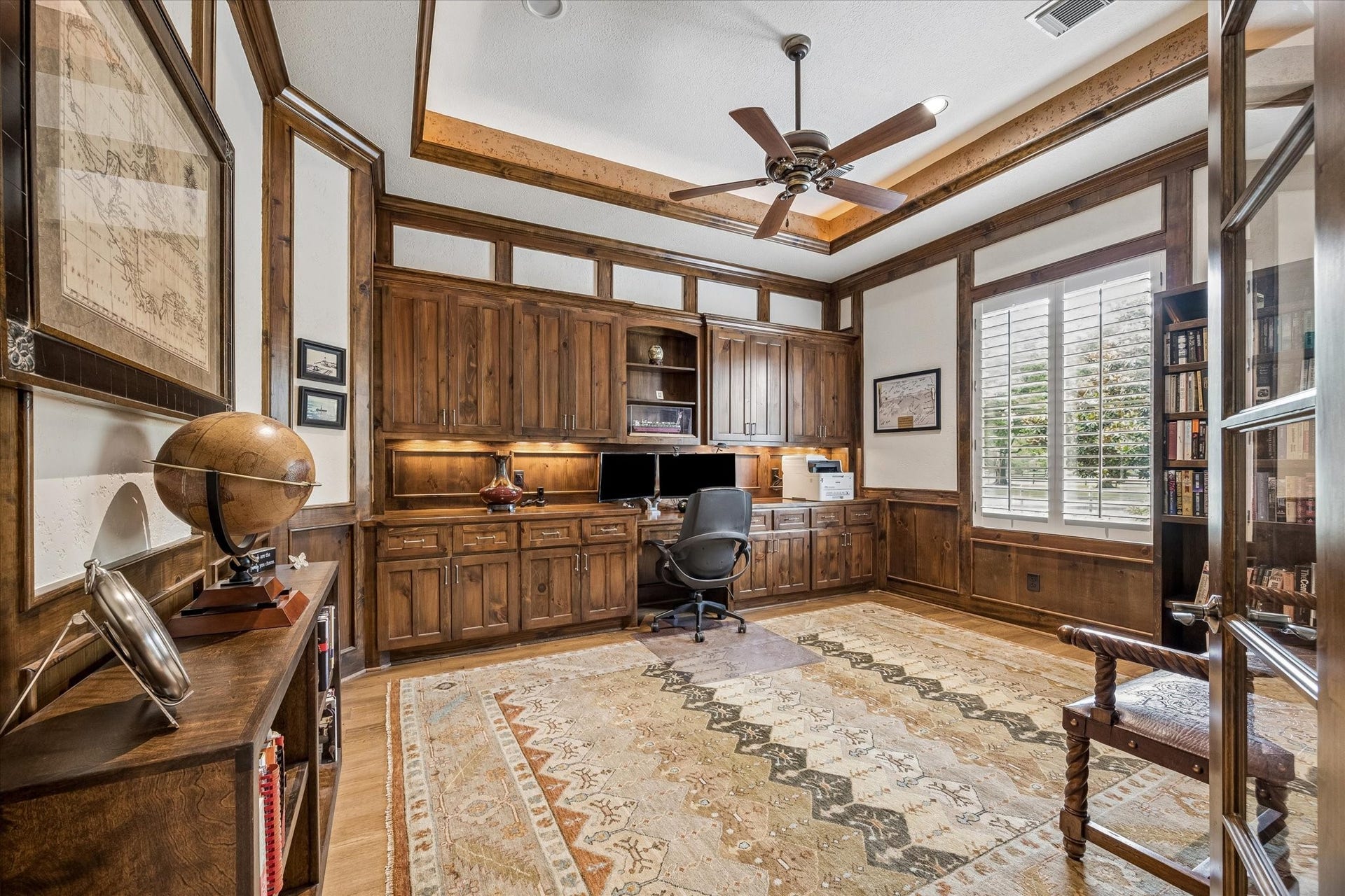 32102 Fulbrook Commons, Fulshear, TX 77441 Custom built-ins and extensive millwork create a distinguished study designed for productivity and inspiration. Tray lighting, glass double doors, and beautiful windows with plantation shutters are more features in this spacious private home office.
