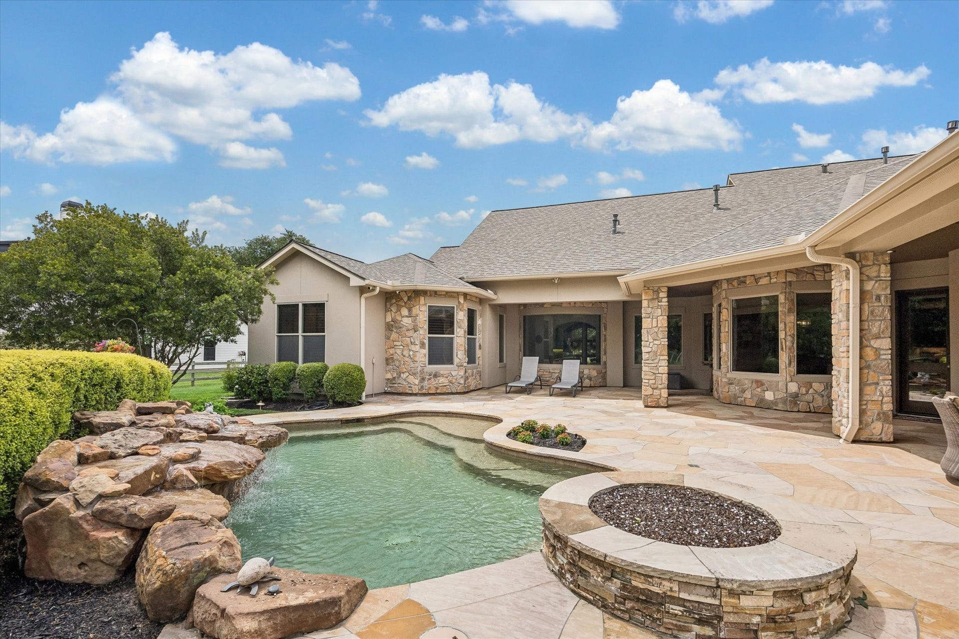 32102 Fulbrook Commons, Fulshear, TX 77441 Thoughtfully crafted stonework, lush landscaping, and multiple gathering spaces create a seamless extension of the home's luxury living areas. Surrounded by mature trees and open green space, the pool area feels private, peaceful, and designed for both recreation and relaxation.
