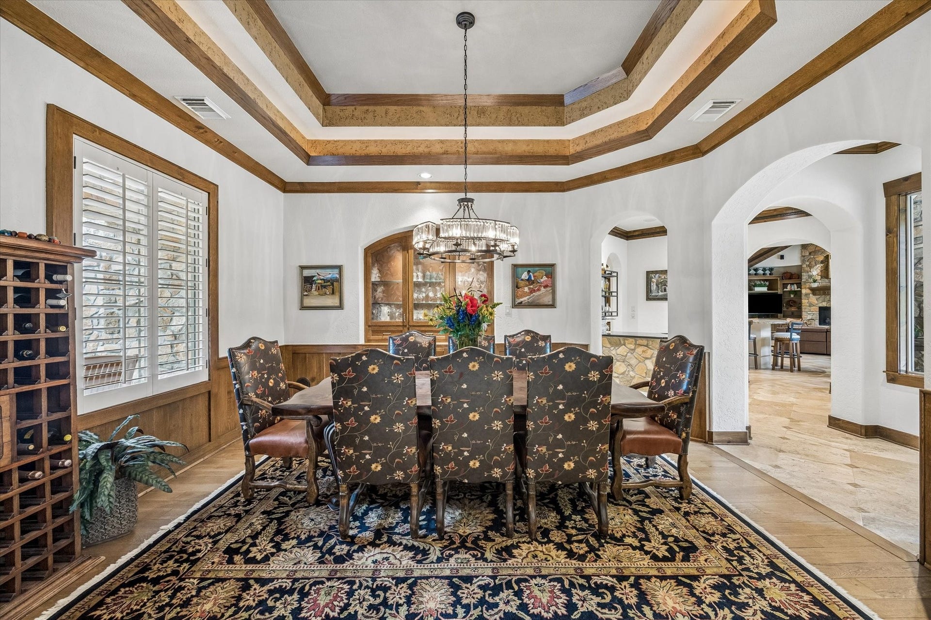 32102 Fulbrook Commons, Fulshear, TX 77441 Intricate ceiling treatments and graceful archways lend a refined atmosphere to this formal dining space. Front facing windows with plantation shutters, a built in storage cabinet with lighting and shelving, and rich wood paneling add elegance to the formal dining room.