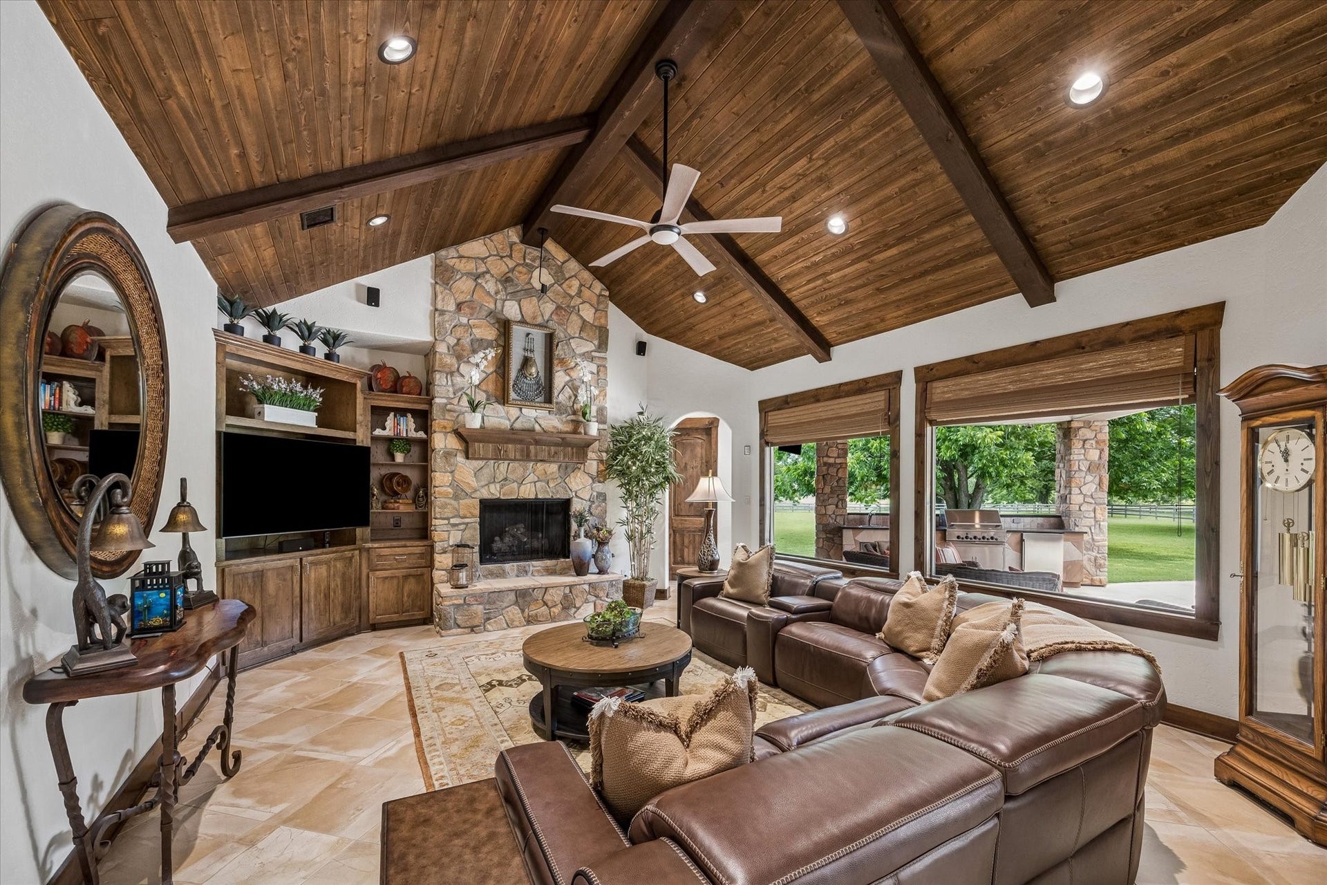 32102 Fulbrook Commons, Fulshear, TX 77441 A vaulted wood-plank ceiling and floor-to-ceiling stone fireplace with large windows serve as stunning focal points in the heart of the home.