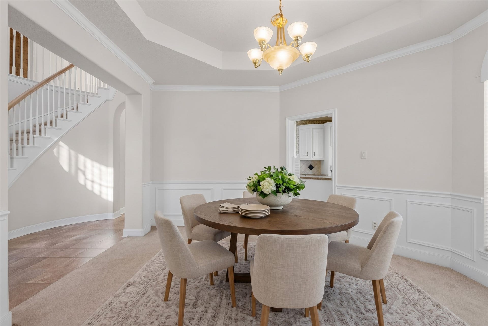 4402 Santee Drive, Baytown, TX 77521 Refined dining space showcasing detailed wall trim, decorative sunburst window transoms, a central chandelier, and convenient swinging-door access to the kitchen.