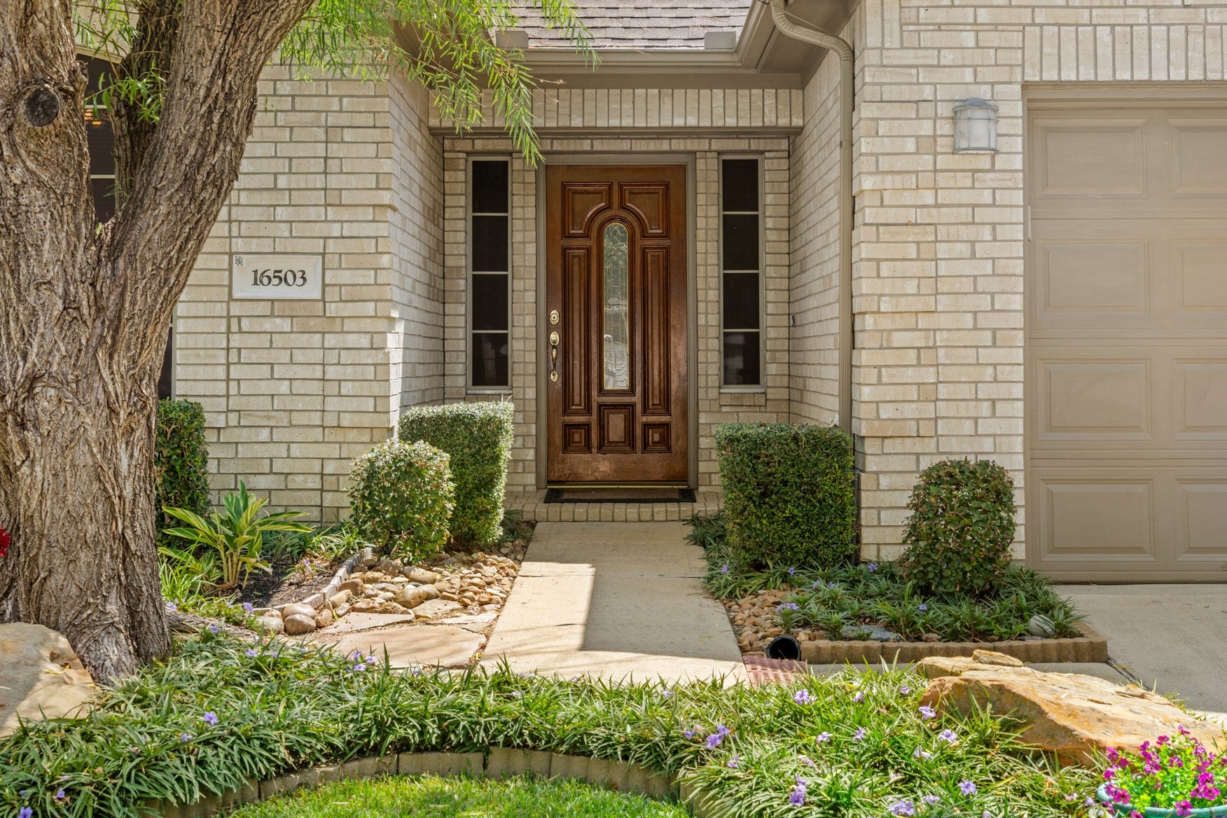 16503 Oat Mill Drive, Houston, TX 77095 A welcoming entrance with stone-lined pathways and mature landscaping!