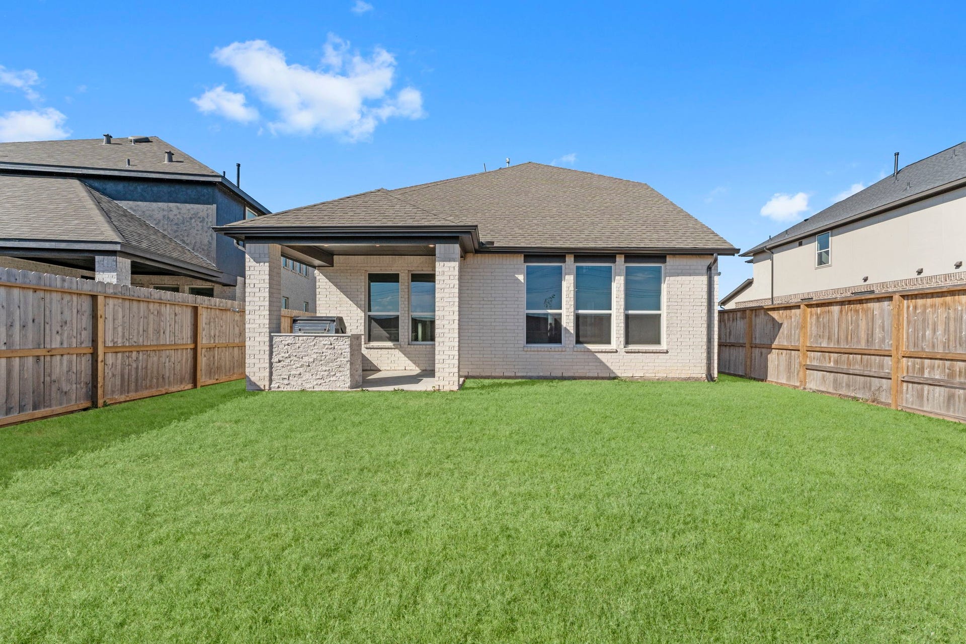 2230 Fresh Flower Way, Richmond, TX 77406 A wide view of the rear elevation highlighting the contemporary brick exterior and the private, fenced-in perimeter. This home features 100% Brick, no siding!